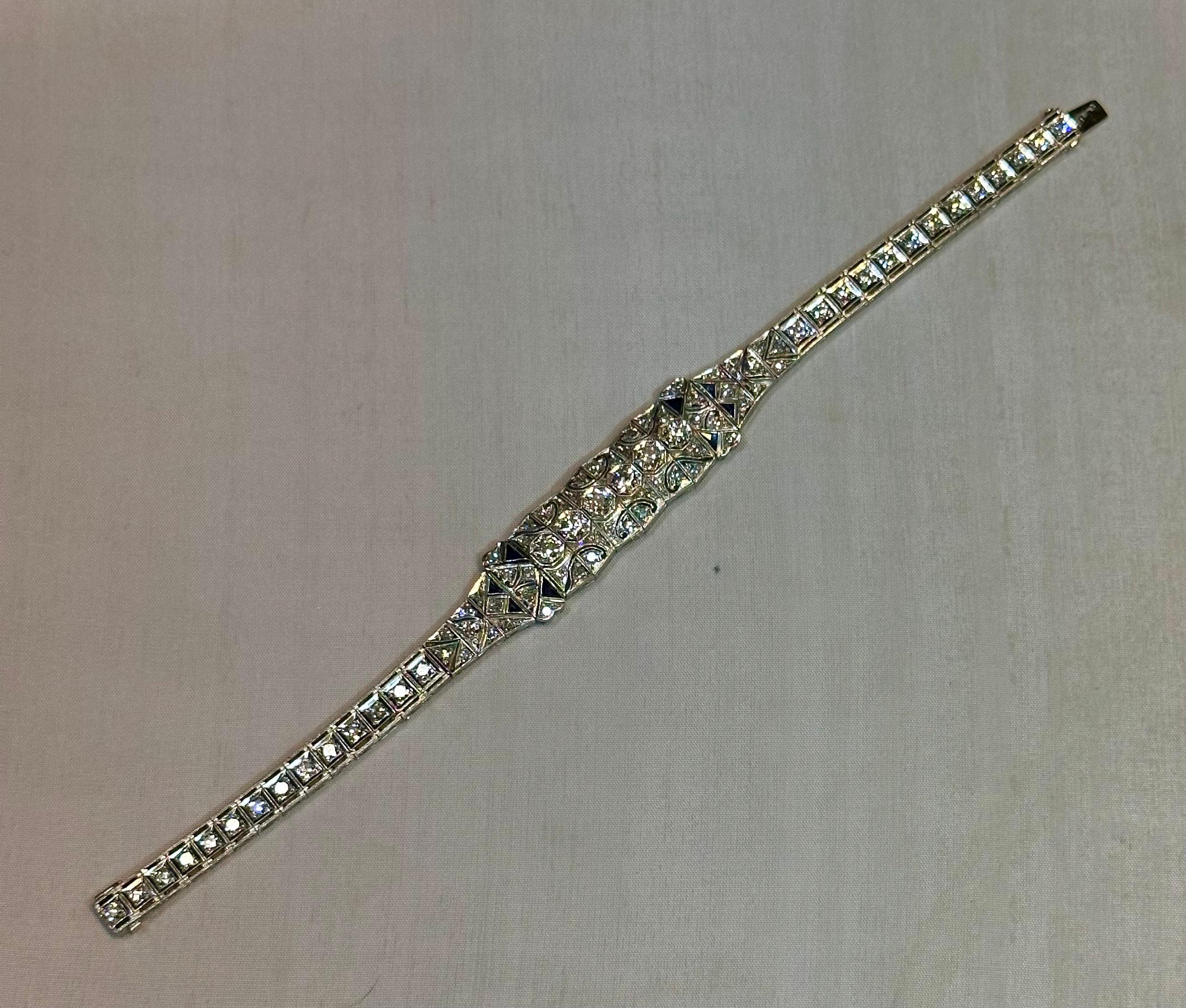 This vintage early 20th century Edwardian (1902 - 1918) diamond bracelet is elaborately designed in platinum & multiple precious gems. The bracelet center features six embellished center panels with sparkling round faceted diamonds. The center