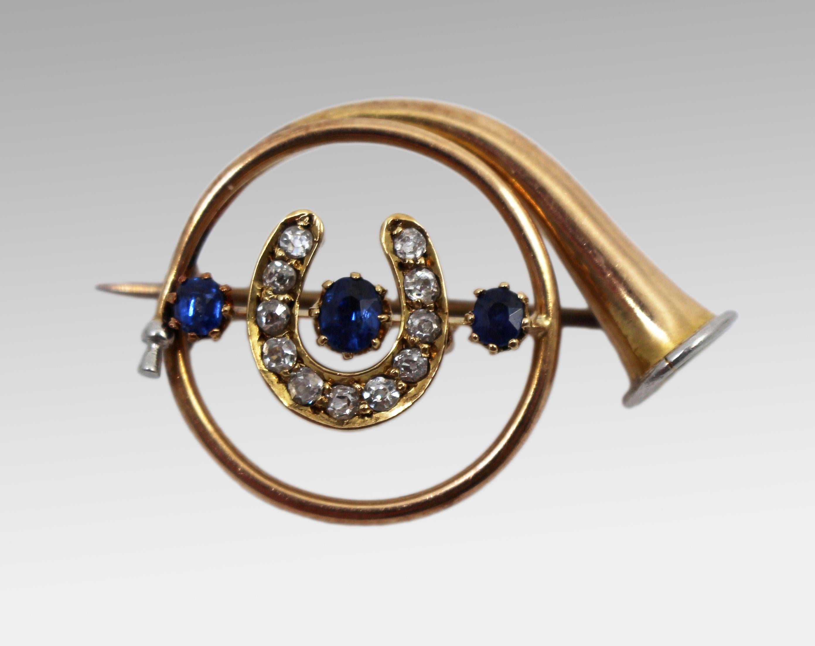 Spilla a forma di corno da caccia in oro con zaffiro e diamanti, Inghilterra, 1905 circa
Una raffinata spilla edoardiana a forma di corno da caccia arrotolato, ornata al centro da un motivo a ferro di cavallo, simbolo tradizionale di fortuna. Il
