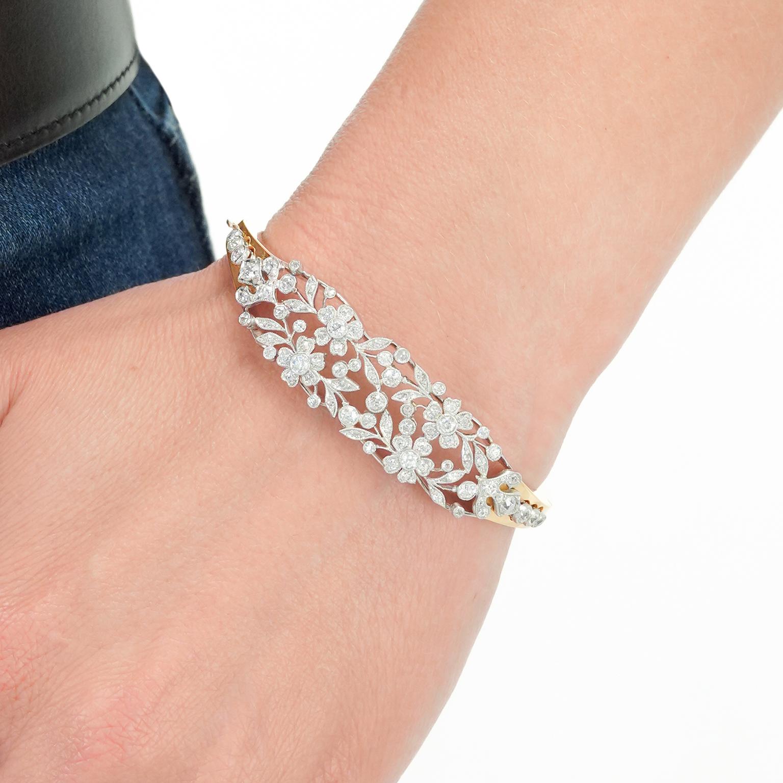 Circa 1950s/1900s, Platinum and 14k, American. This cheerful floral bracelet is gorgeous. Edwardian platinum and diamond flowers, leaves, twigs, and berries on top underscored by a heavy yellow gold bracelet. This stunning marriage has it all,