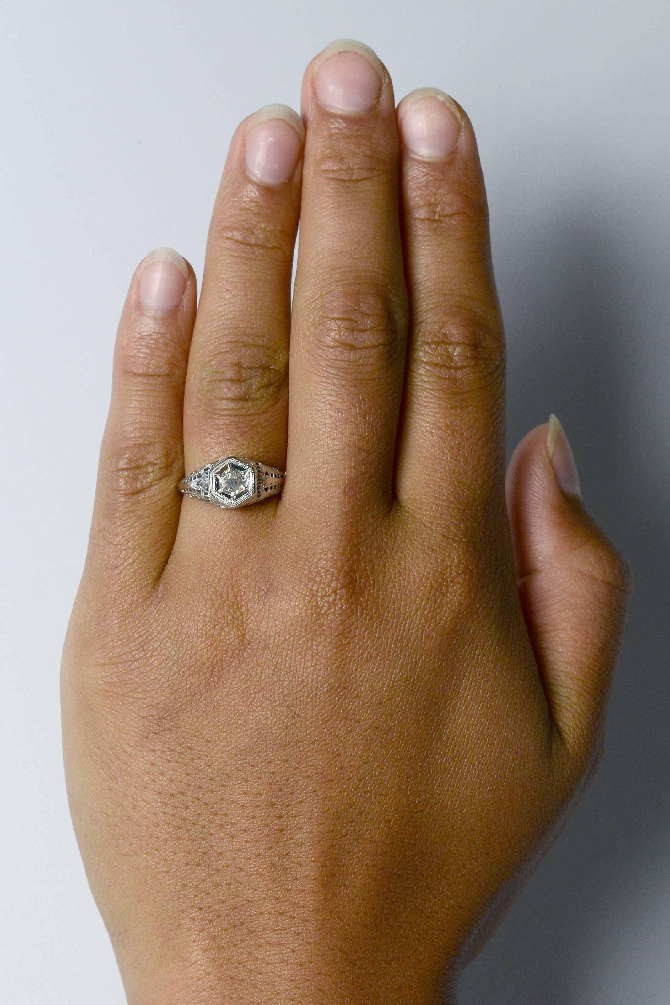 La bague de fiançailles solitaire à diamants Stockton, de l'époque édouardienne, présente une forme élégante et épurée, un anneau filigrané effilé et une monture hexagonale de style Art déco. Un diamant brillant de taille ancienne d'un peu moins de