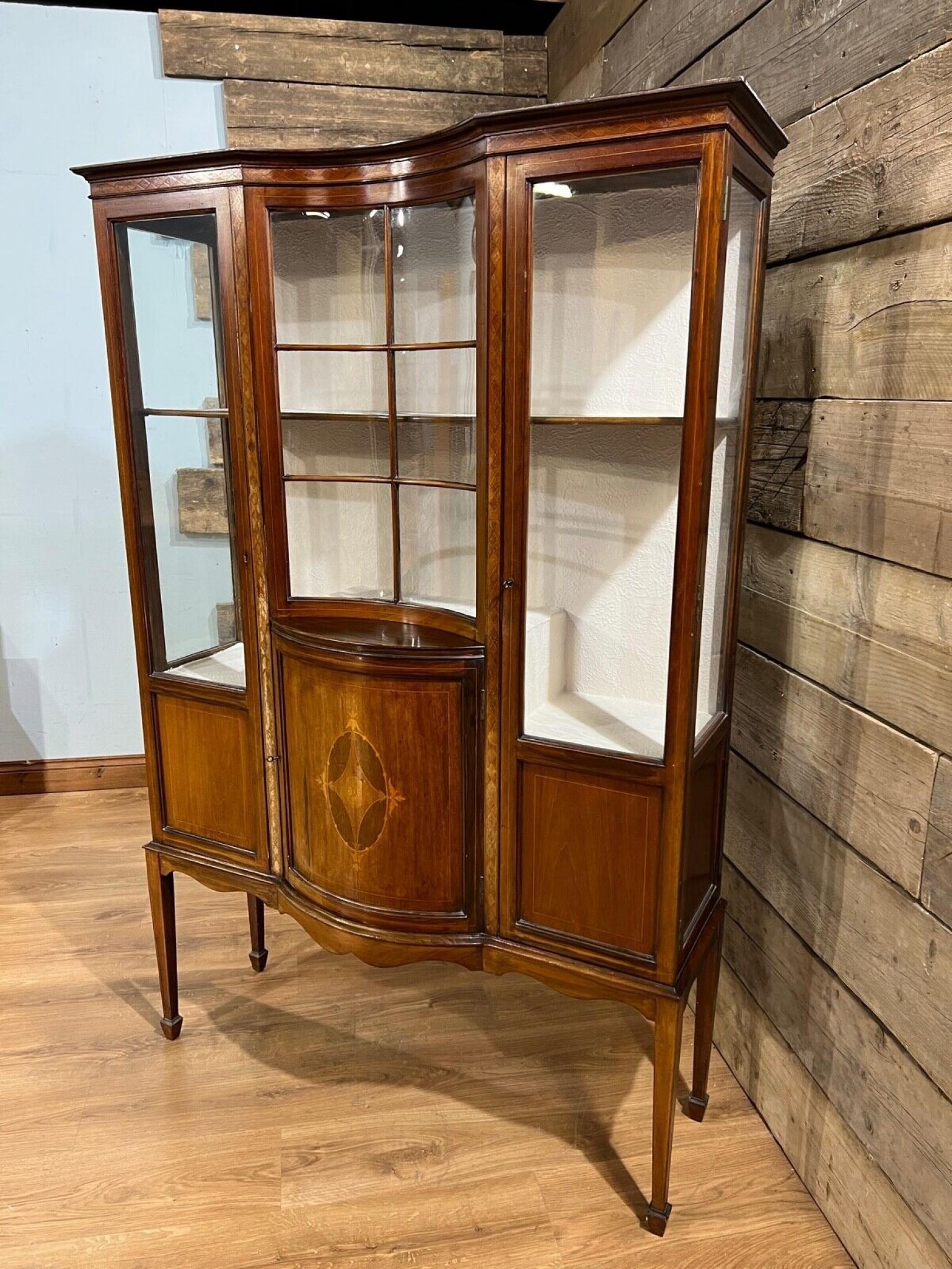 Gorgeous period Edwardian display cabinet in mahogany
Features intricate inlay work
Two doors open out either side of the central section which features curved glass
Circa 1900 on this clean antique cabinet
Offered in great shape ready for home use