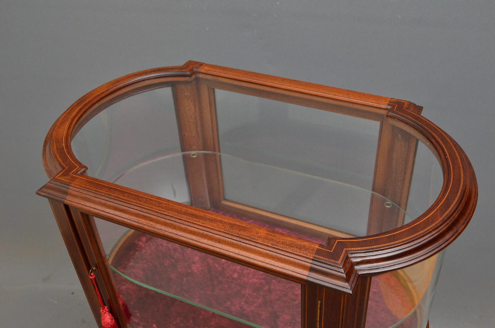 Sn4383, a fine example of Edwardian, mahogany display table of oval outline, having satinwood inlaid top and door enclosing glass shelf, standing on elegant, string inlaid legs terminating in spade feet, all in home ready condition, circa