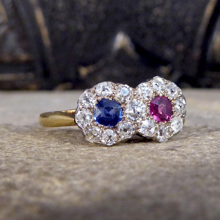 An absolutely stunning Edwardian piece. This ring features two Daisy clusters one with a bright blue Sapphire and the other a vibrant Ruby in the centre with a total of 15 Old Cut Diamond surround forming a double Daisy Cluster style with an 18ct
