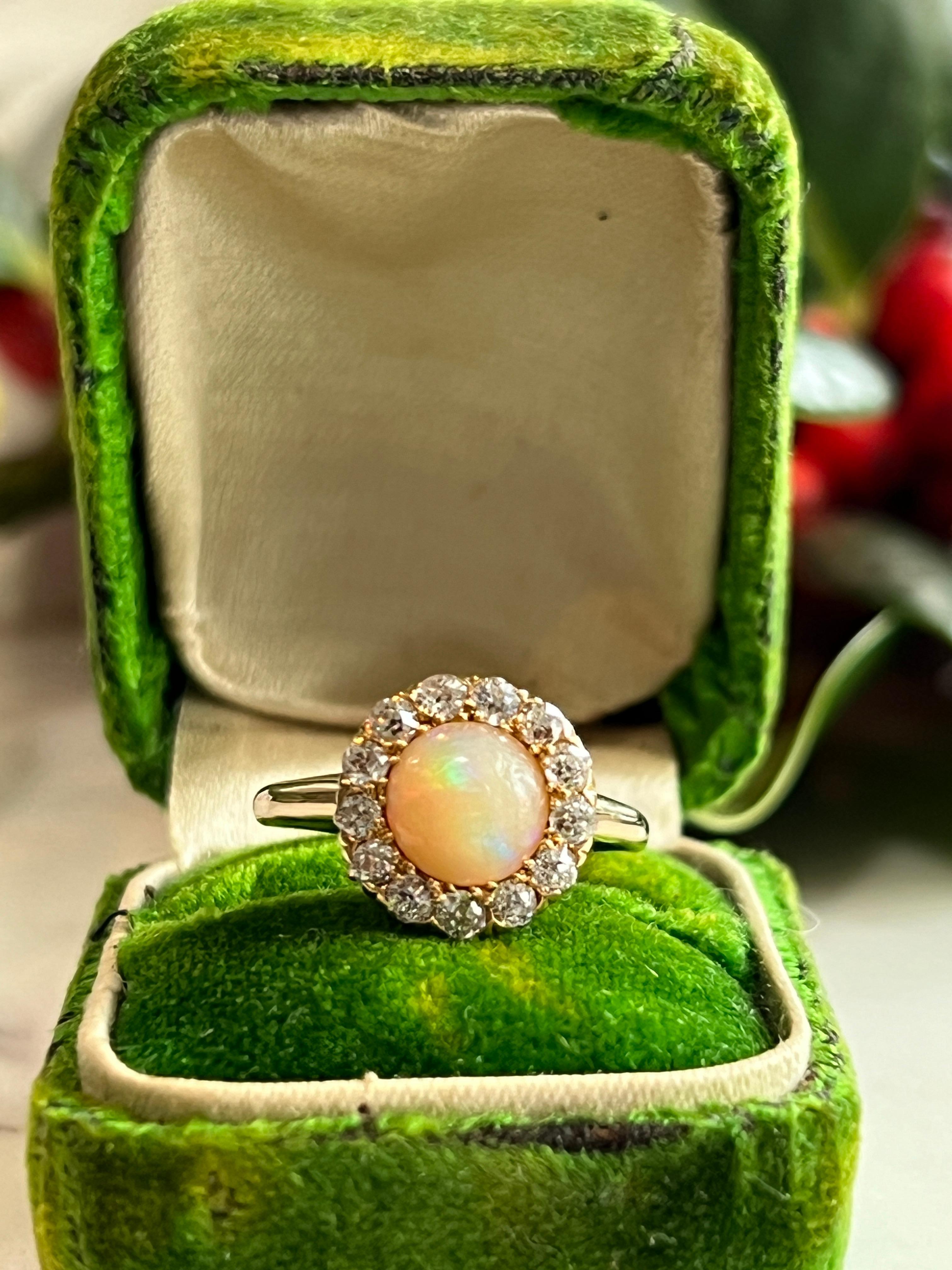 This lovely late Victorian/Early Edwardian opal and diamond ring circa 1900s, is crafted in 14 karat yellow gold. It features a mesmerizing 7mm round opal, weighing approximately 0.16 carats, displaying its signature play of color. Encircling the