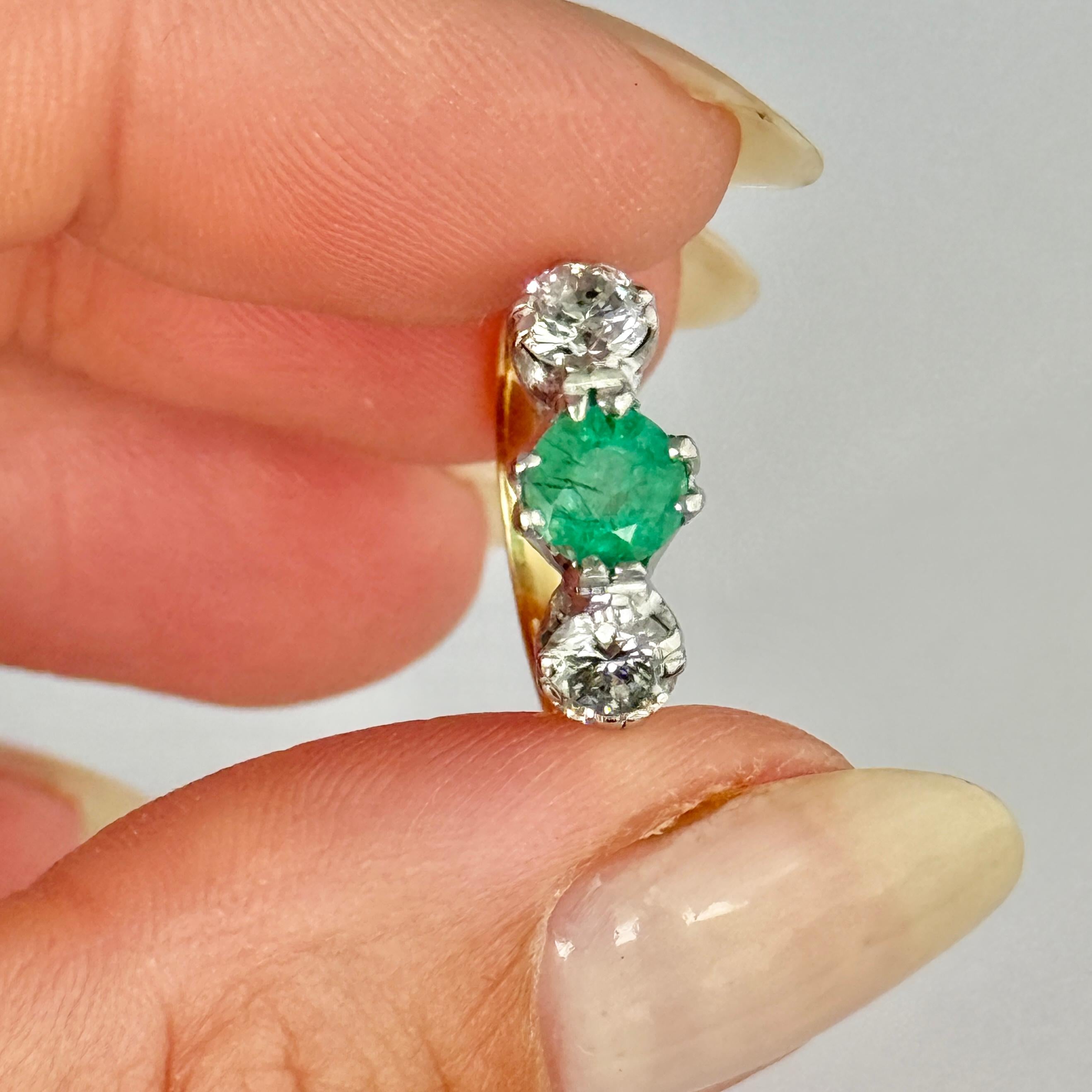 L'émeraude centrale est très belle et brillante et mesure environ 65pts. De chaque côté, deux diamants brillants sont posés, chacun mesurant environ 35pts. La bague est modelée en or 18ct et les pierres sont serties en platine.

Taille de la bague :