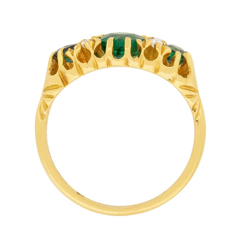 Handmade and dating to 1905, this is ring a unique ring. The ring consists of three emeralds, rich in colour and claw set. The gemstones are natural, the centre weighs 0.85 carat and the other two each weigh 0.20 carat. The small diamonds, which are