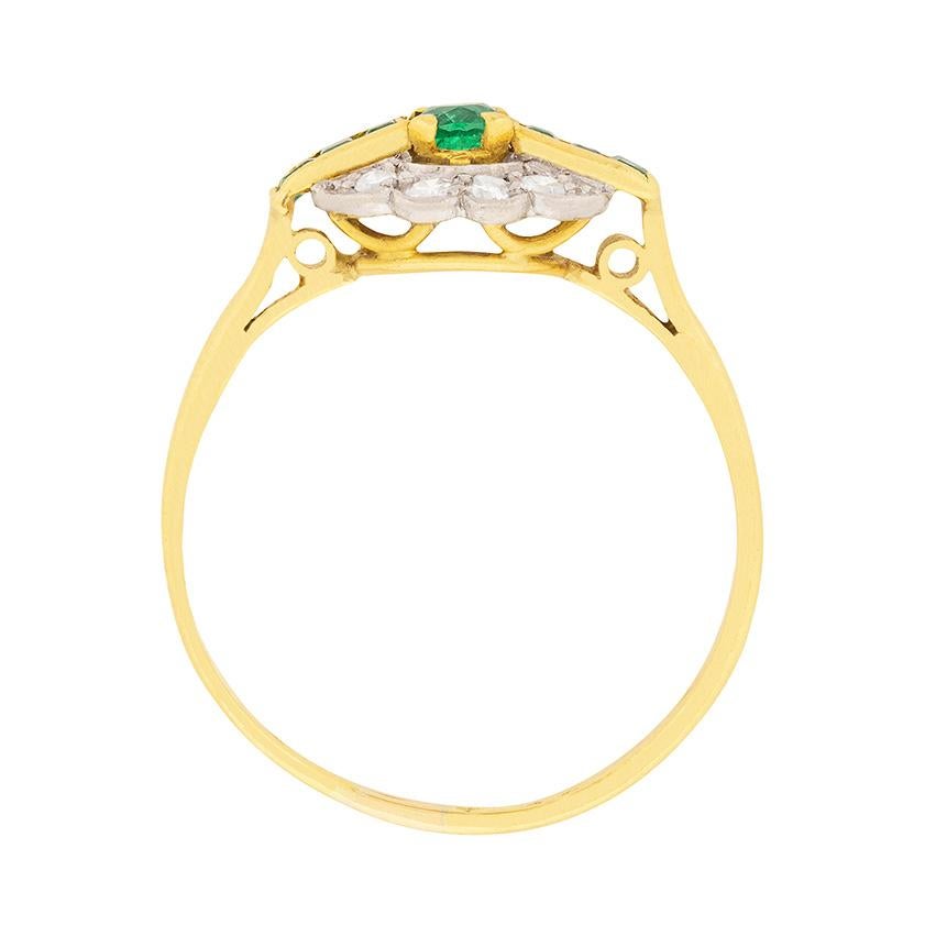 Dating back to 1910, this intricate Edwardian ring is set in both 18 carat yellow gold and platinum. The central 0.20 carat emerald is flanked by 3 baguette cut emeralds on either side. Above and below are four old cut diamonds totalling 0.24
