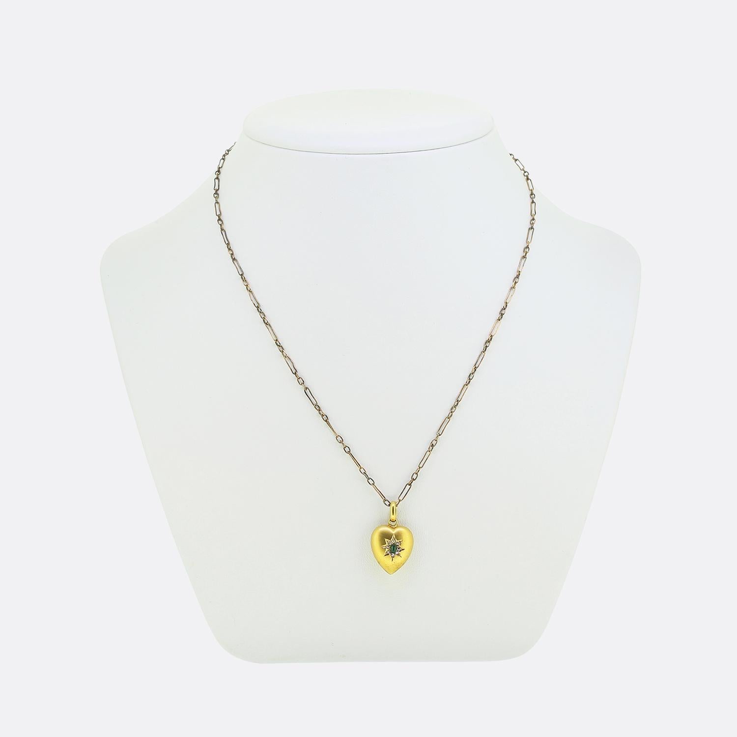 Here we have a charming pendant necklace originally dating back to the Edwardian era. This romantic piece features a heart-shaped pendant crafted from 15ct gold and possessing a smooth matte finish. At its centre lies a green emerald surrounded by