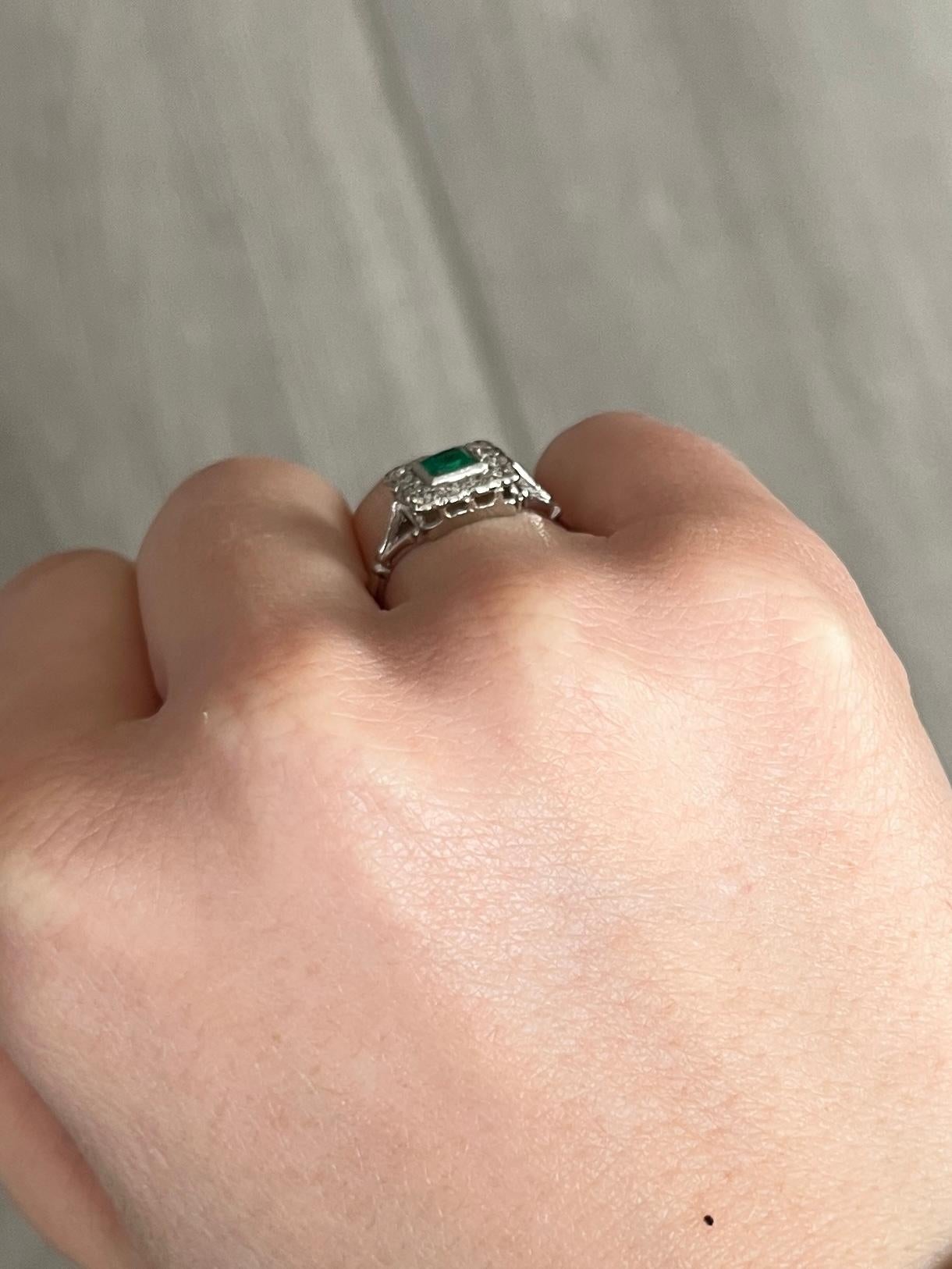 A superb antique Edwardian panel ring centrally set with a classic square-cut green emerald measuring 40pts. The emerald is bordered by beautiful white diamonds totalling aprox 36pts. The ring is modelled in platinum. 

Ring Size: N 1/2 or 7
Panel