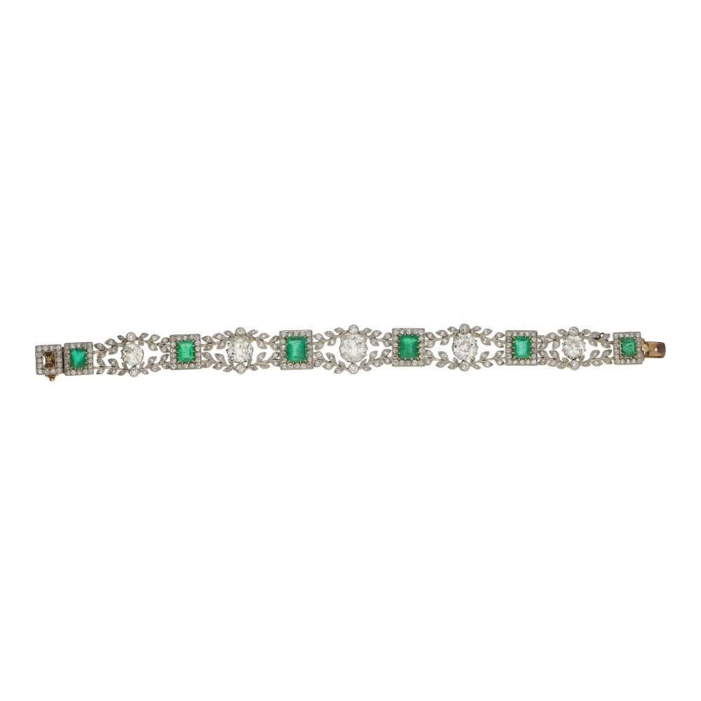 A beautiful Edwardian emerald and diamond bracelet in platinum and gold. The bracelet is formed of five old European cut diamonds claw set and graduating in size from the centre. The diamonds are centrally set to a mile-grain edged floral motif