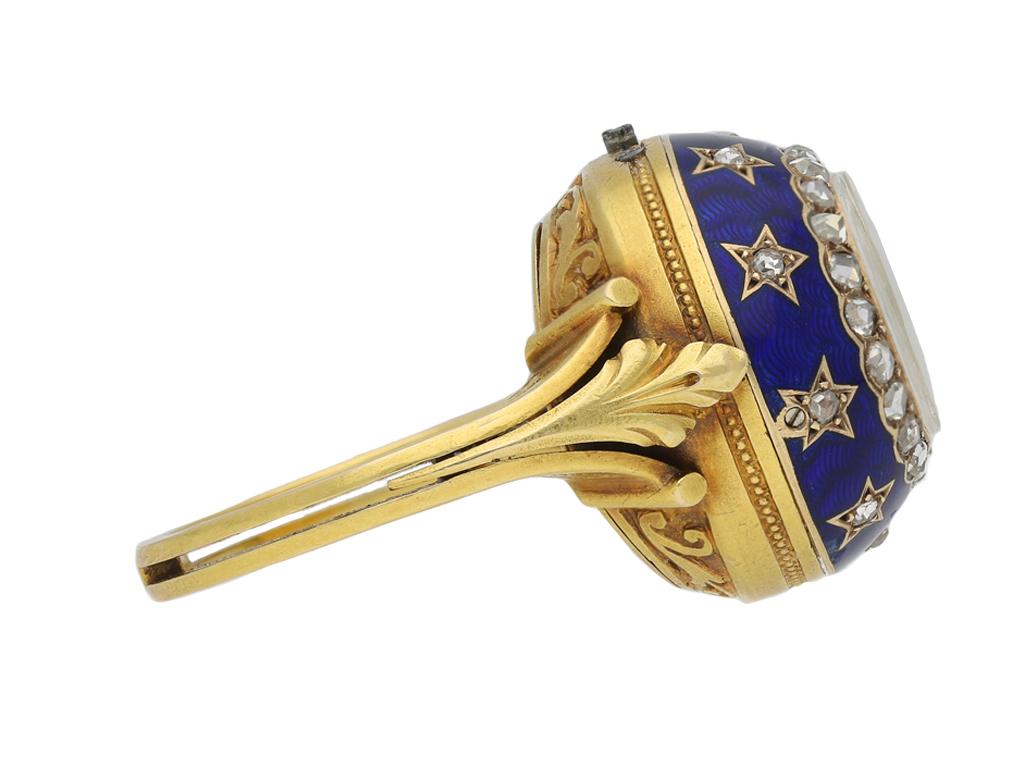 Edwardian enamel and diamond watch ring. Set with thirty one rose cut diamonds in closed back grain and collet settings with a combined approximate weight of 0.31 carats, to an ornate watch ring featuring a circular watch dial with blue and red