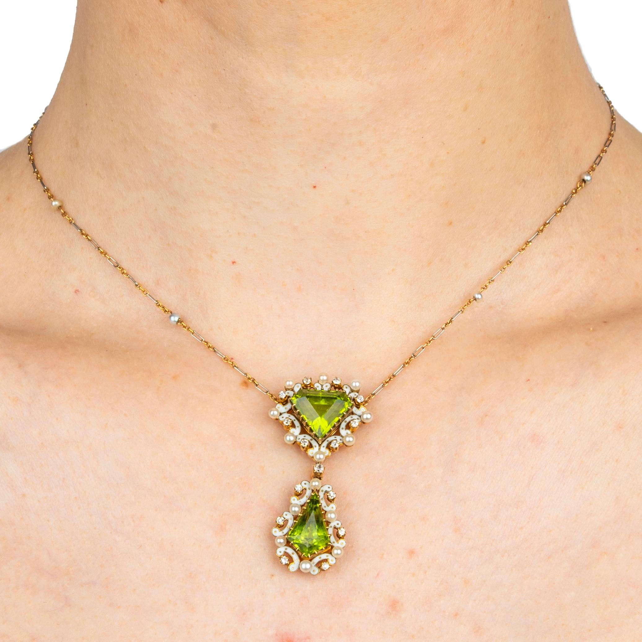 Una bellissima collana inglese di epoca edoardiana, con al centro due peridoti a forma di aquilone - un taglio innovativo per l'epoca - di un vibrante colore verde mela, ciascuno all'interno di bordi in smalto piqué bianco impreziositi da lucenti