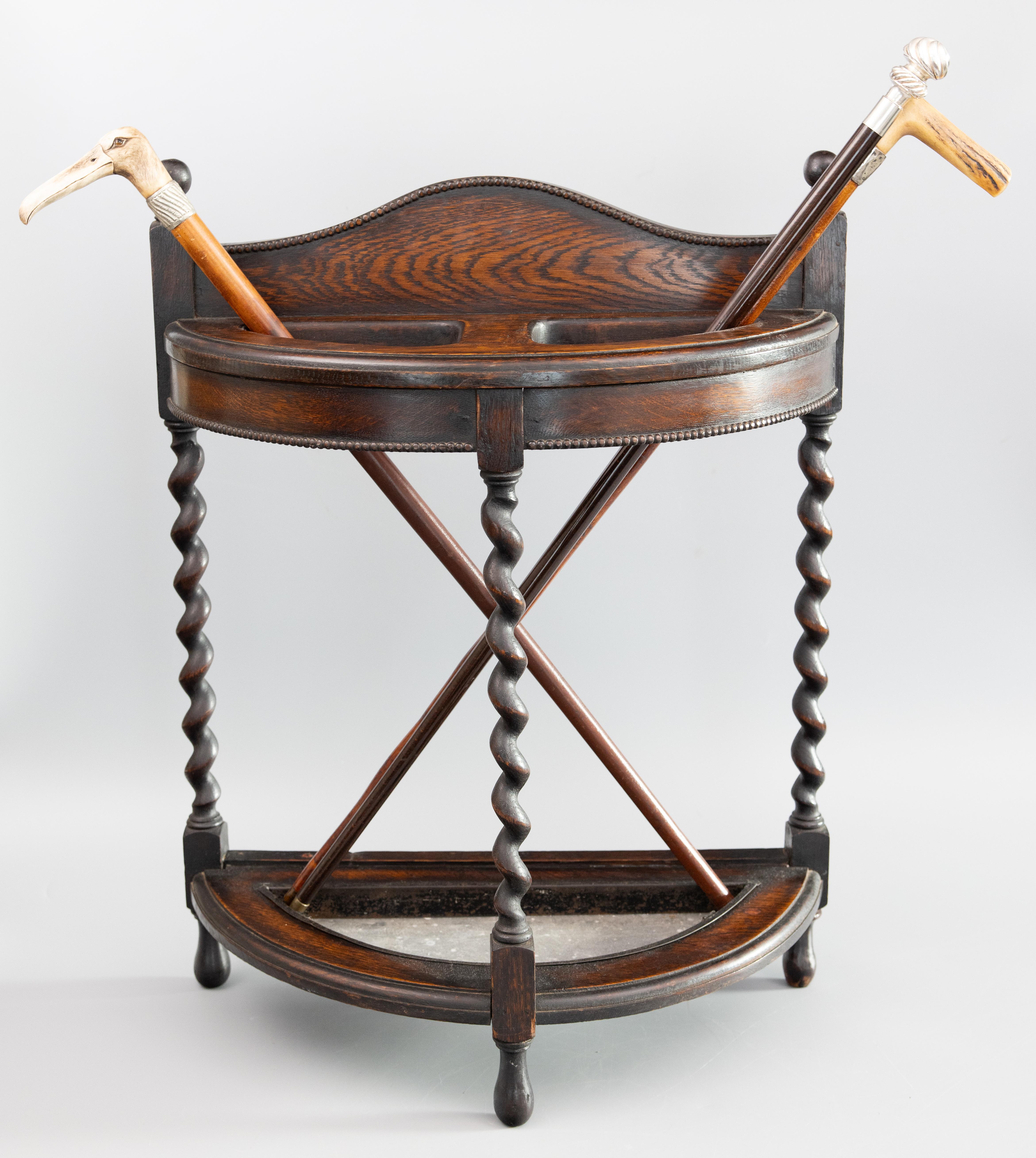 A superb antique English Edwardian oak umbrella or stick stand with hand turned barely twist legs and original drip pan tin liner, circa 1910. This fine quality umbrella stand has a wonderful demi-lune design with beaded trim and would be perfect in