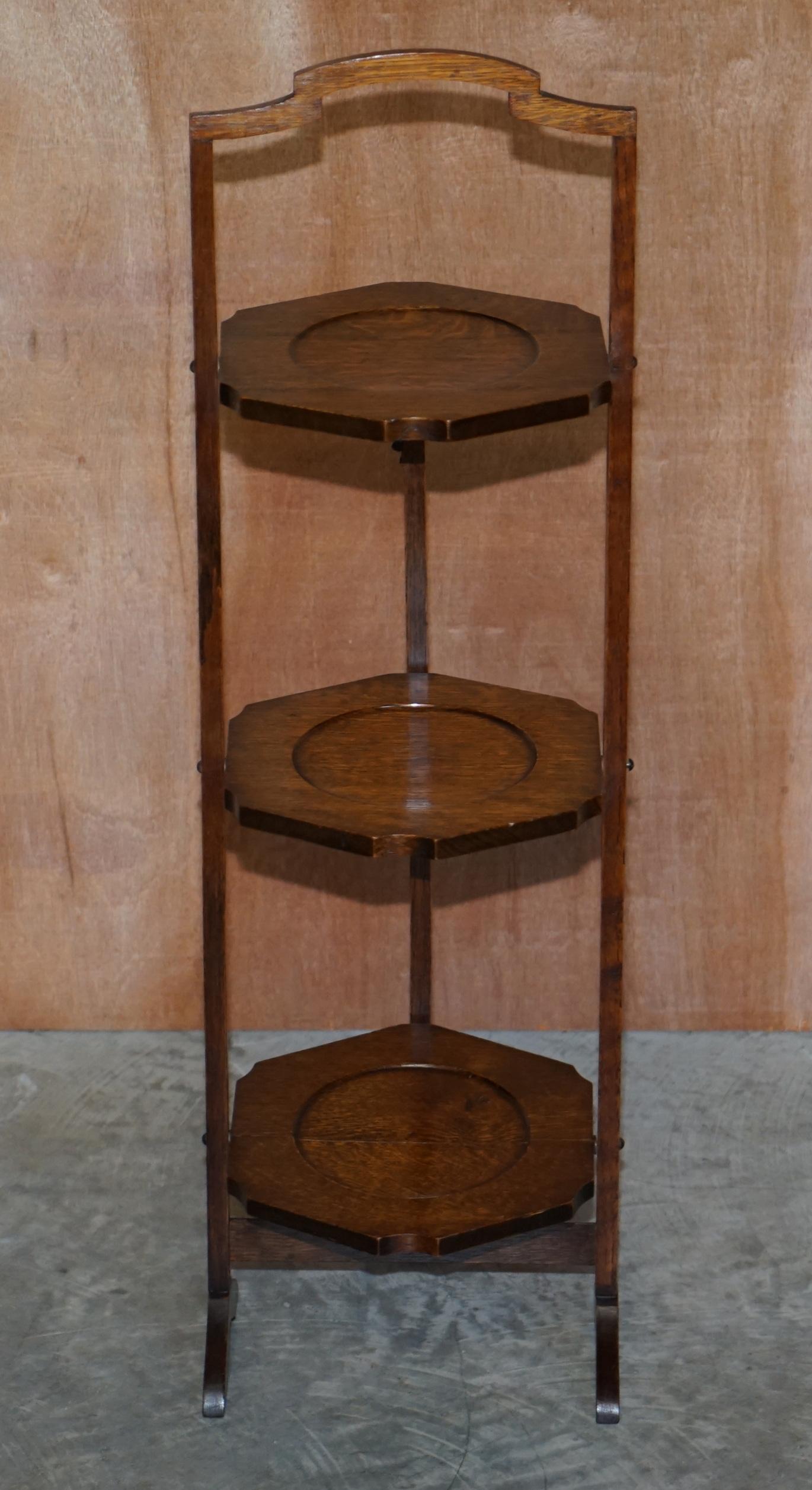 We are delighted to offer this lovely circa 1910 English oak whatnot display stand or folding cake table

A good looking, decorative and well made piece. It can be used for displaying trinkets, small plants or serving cakes. Its made of oak and