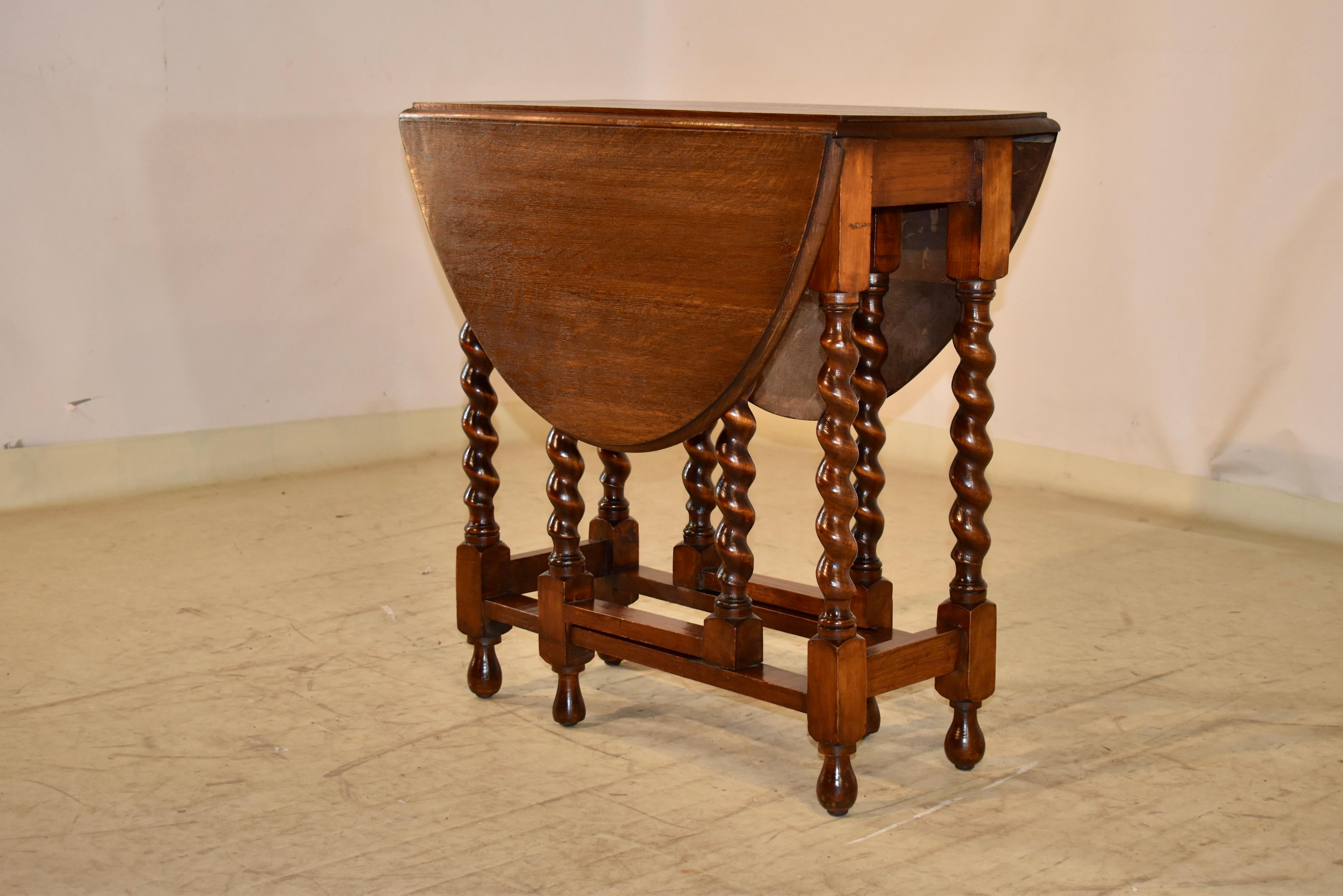 Period Edwardian oak side table from England with a beveled edge around the top.  the top is supported on a simple apron and hand turned barley twist legs and gates.  When the top is open, it measures 41.25 inches in length by 29.5 inches in width. 
