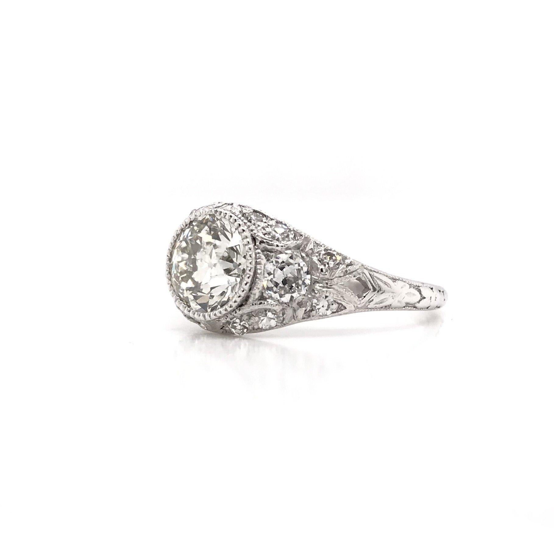 This antique piece was skillfully handcrafted sometime during the Edwardian design period ( 1901-1920 ). Soft, floral, feminine, this Edwardian diamond ring is absolutely unforgettable. The dazzling center diamond is skillfully set in a decorative