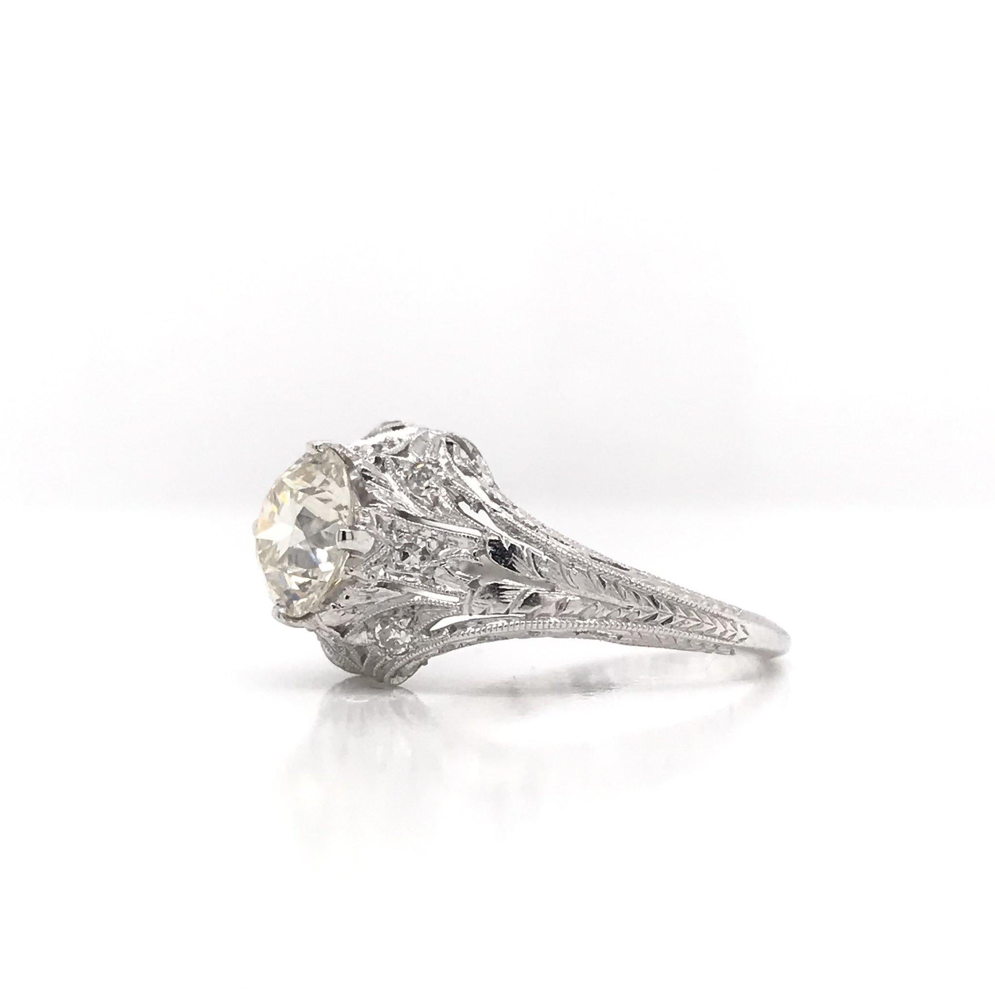 This stunning antique piece was handcrafted sometime during the Edwardian design period ( 1900-1920 ). Antique hand engravings on the inside of the shank indicate the ring was dedicated 12/25/20. The center diamond measures approximately 1.54 carats