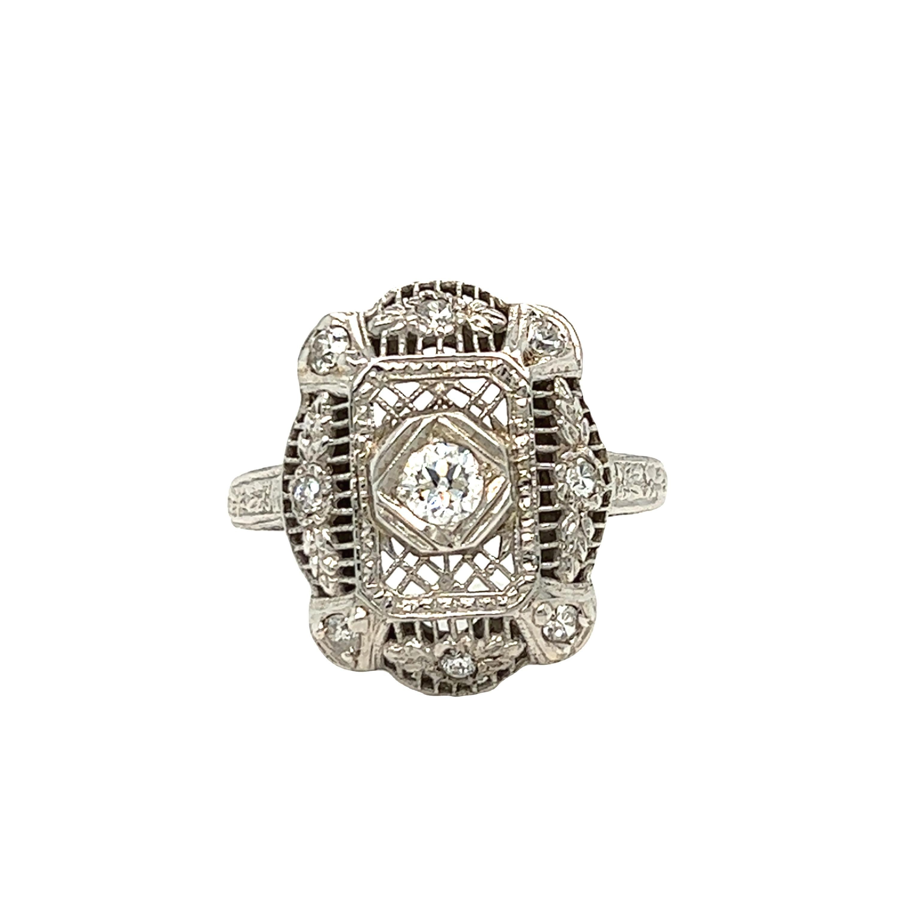 An old European cut diamond weighing approximately .45 carat - H color with VS2 clarity is centered in an antique Edwardian era 18K white gold ring with single cut diamond accents weighing collectively 0.24 - eye clean and bright. The ring displays