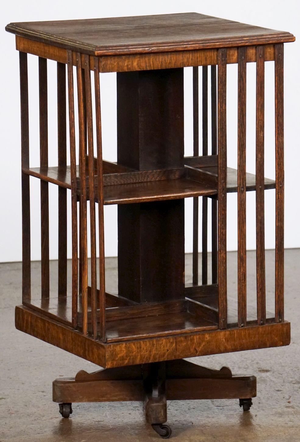 A fine English revolving book stand of oak from the Edwardian era, featuring a two-tiered bookcase sub-divided into eight shelving compartments, with a moulded square top connecting the lower two tiers with vertical latticed slats. The entire unit
