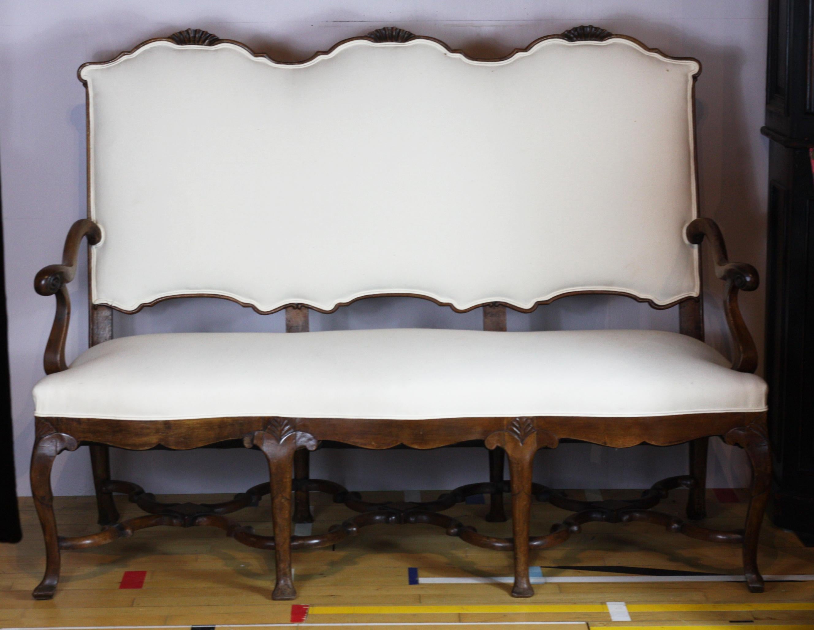 Edwardian solid walnut French sofa, raised on 8 cabriole legs connected with elegant carved stretchers, with repeated shell motif on top rail and scrolling on the walnut arms circa 1900, in superb condition, recently
re-upholstered in calico.