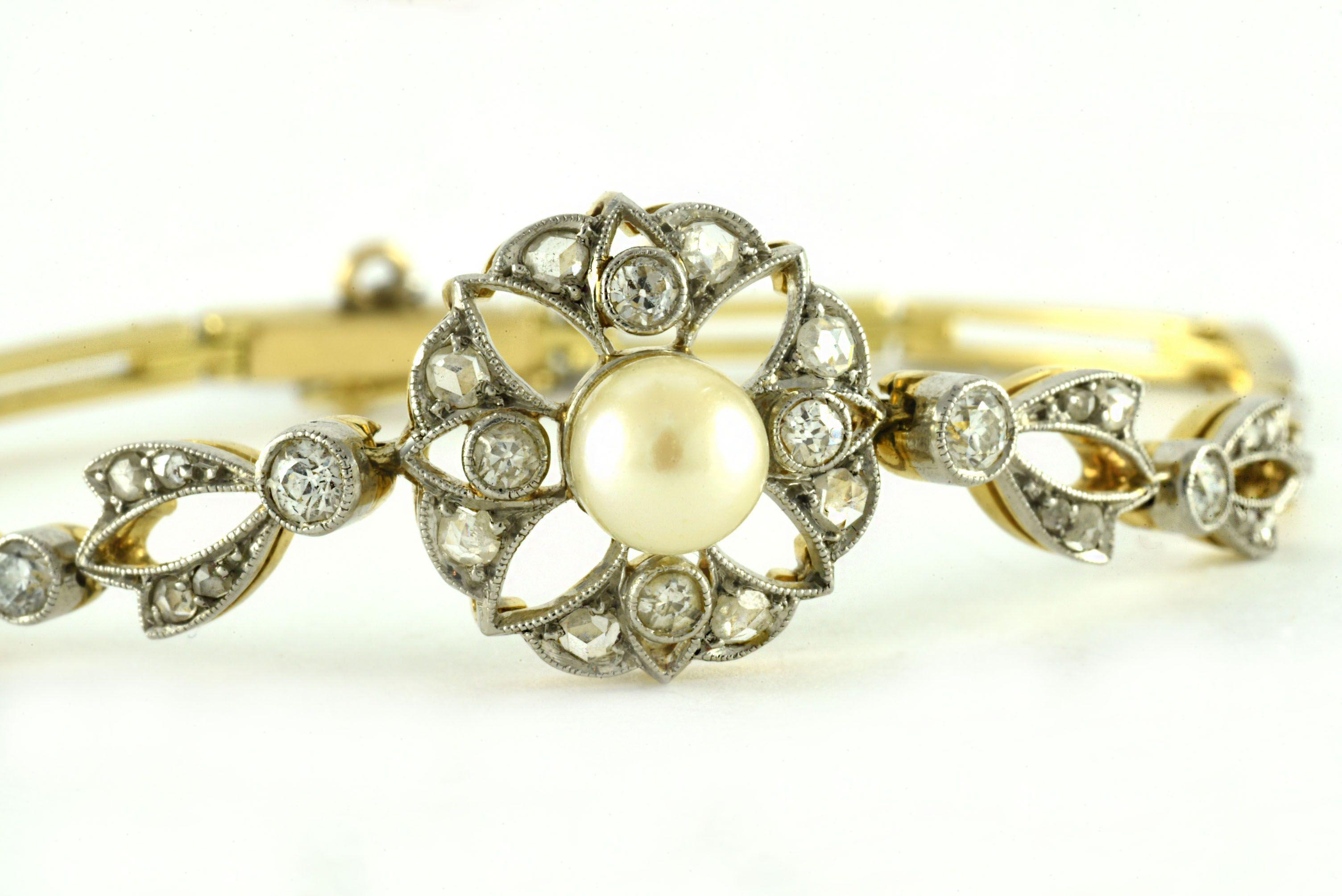 This delicate Edwardian era bracelet is designed around a single white pearl measuring 5.37mm surrounded by a mix of eight Old European and Old Mine cut diamonds totaling 0.47 carats, F-G color, VS-SI1 clarity in a floral surround and accented by
