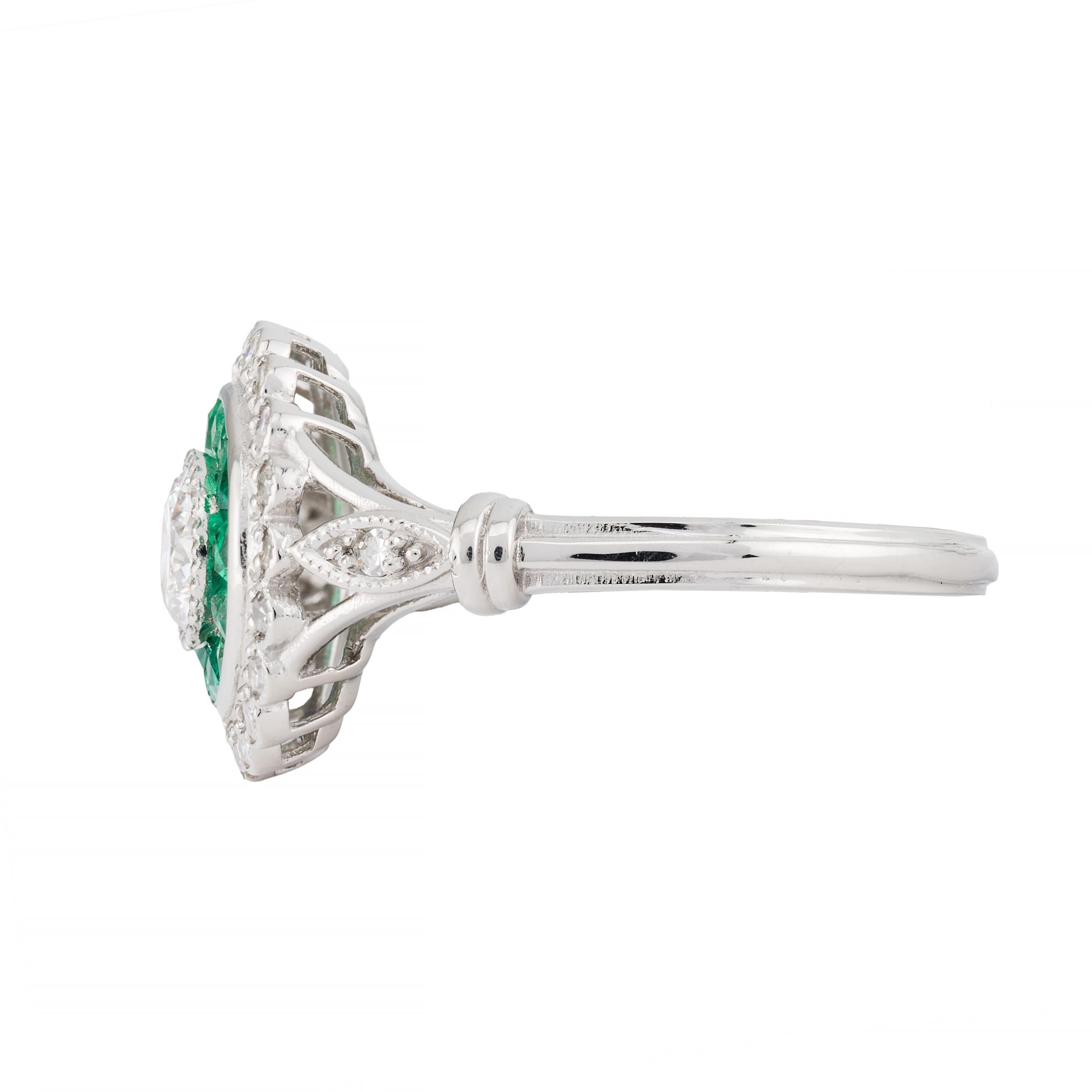 Aston Estate Jewelry Presents:

An exquisite engagement ring featuring a 0.42 carat European cut diamond, with a clarity of VS2 and an H color grade. The central diamond is encircled by 0.42 carats of French cut emeralds, showcasing a vibrant green