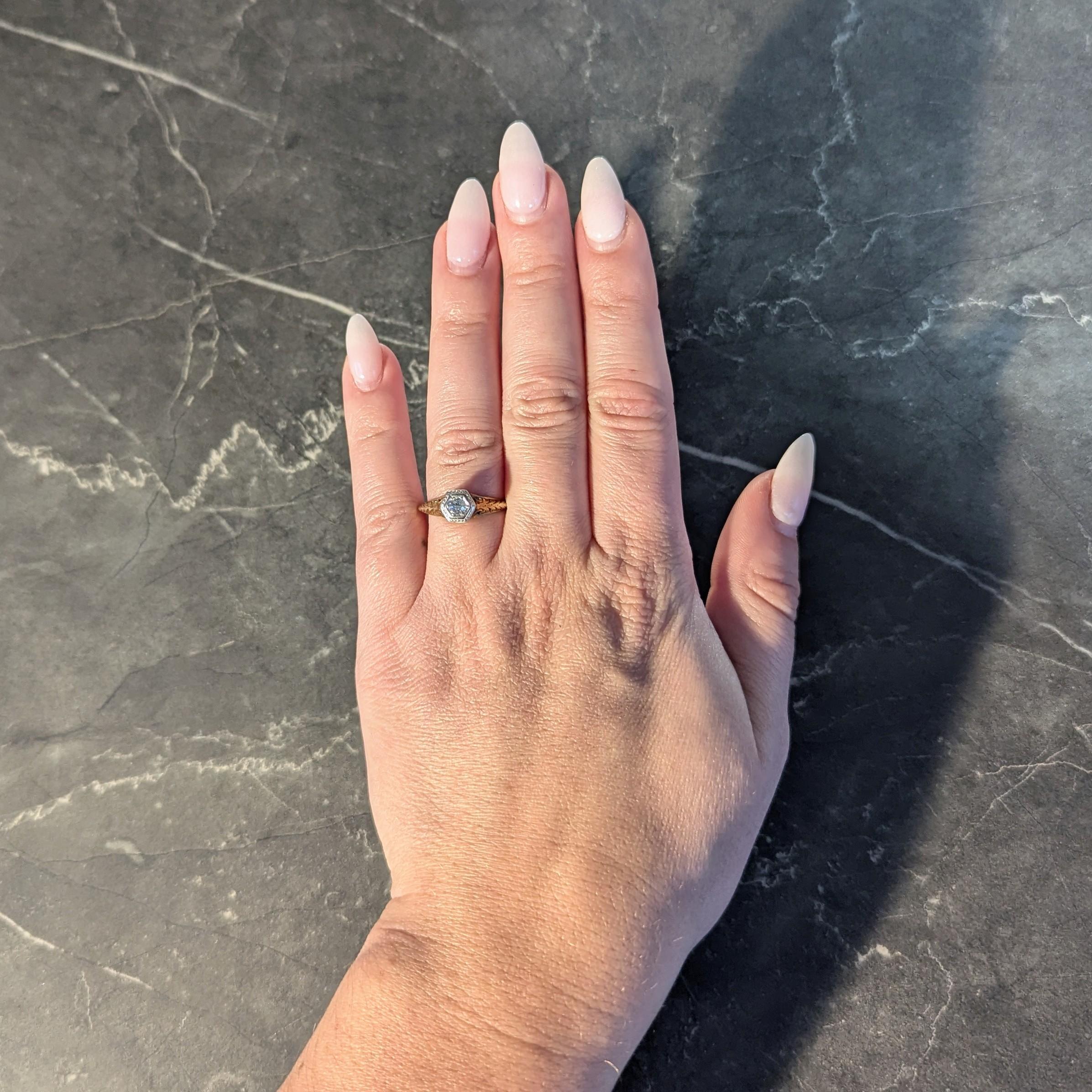 Centering an old European cut diamond weighing approximately 0.17 carat - H color with SI1 clarity
Bead set in a platinum-topped and pierced hexagonal form head
Engraved with geometric motif with a pierced yellow gold gallery
Displaying a scrolling