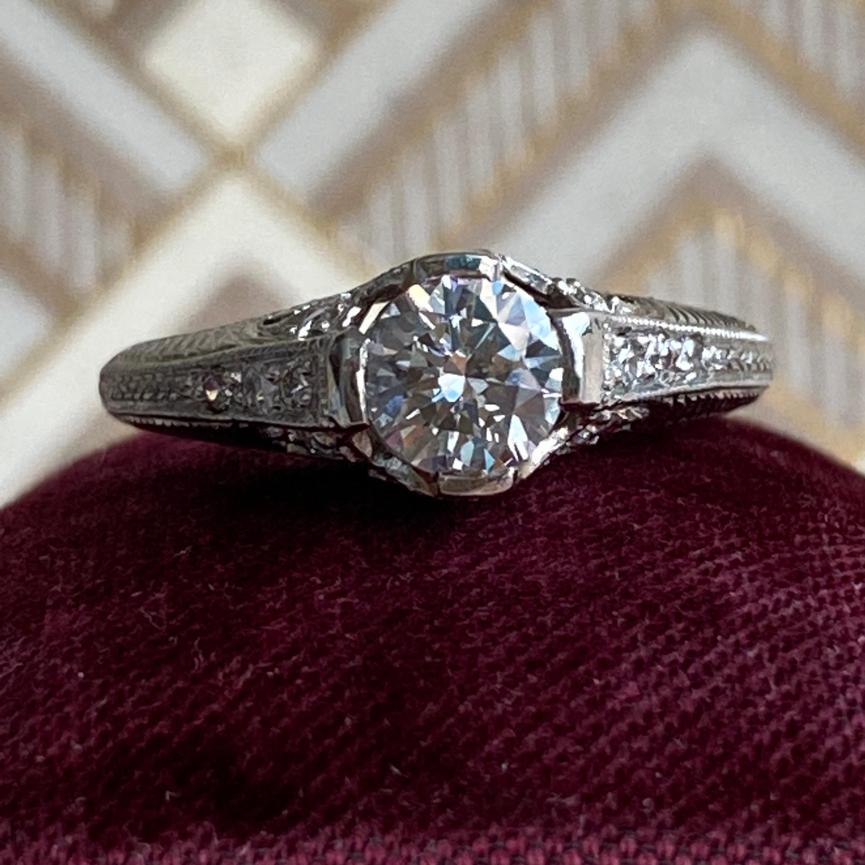 Details:
Lovely Edwardian platinum and diamond engagement ring (dates 1900-1910). Delicate design with a delicate hand cut filigree with engraved details surrounding the elegant detailed mounting. The engraving goes half around the band. The height