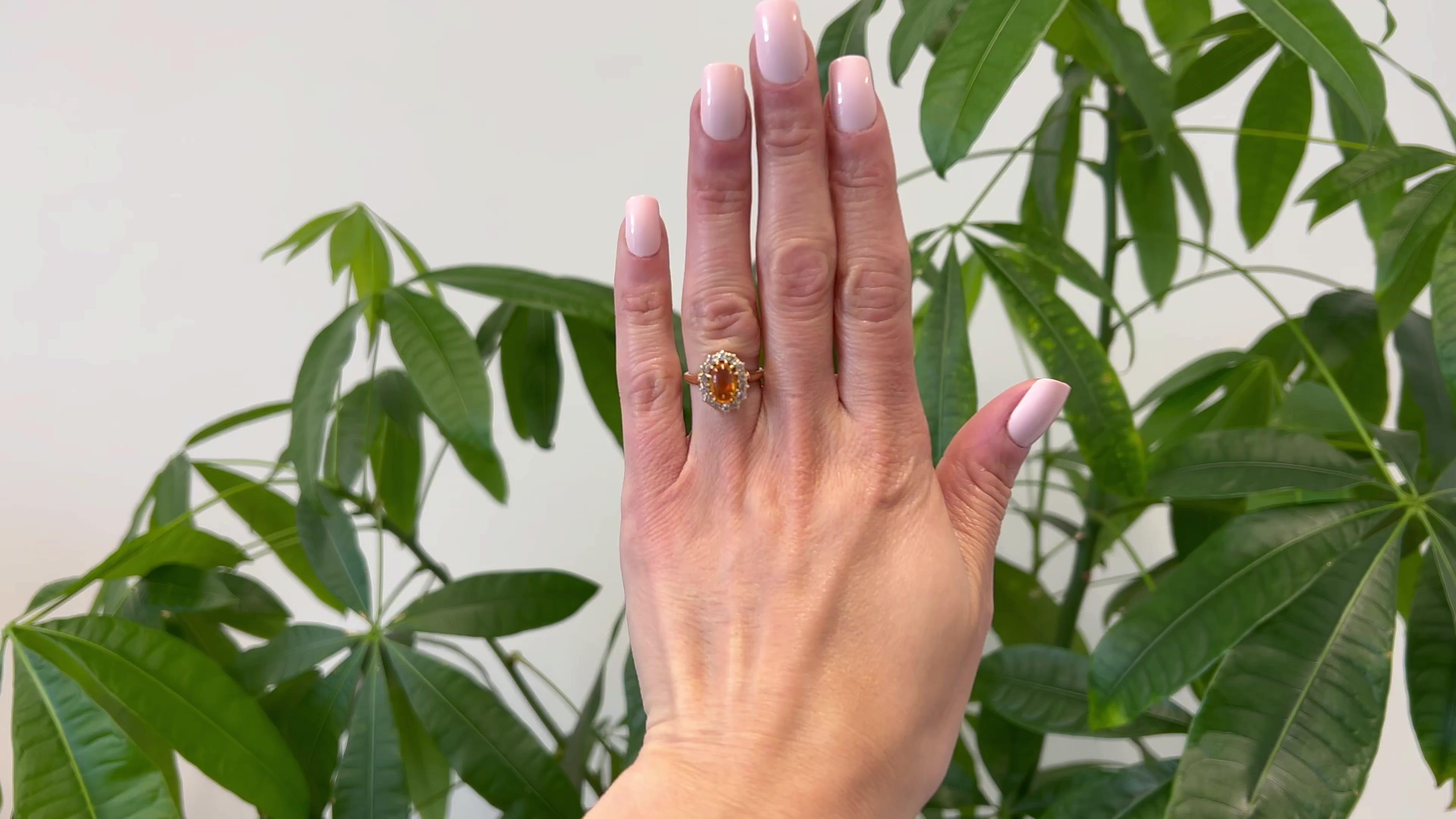 One Edwardian Fire Opal Diamond 14k Rose Gold Cluster Ring. Featuring one cabochon fire opal weighing approximately 1.30 carats. Accented by 14 old European cut diamonds with a total weight of approximately 0.65 carat, graded I color, SI clarity.