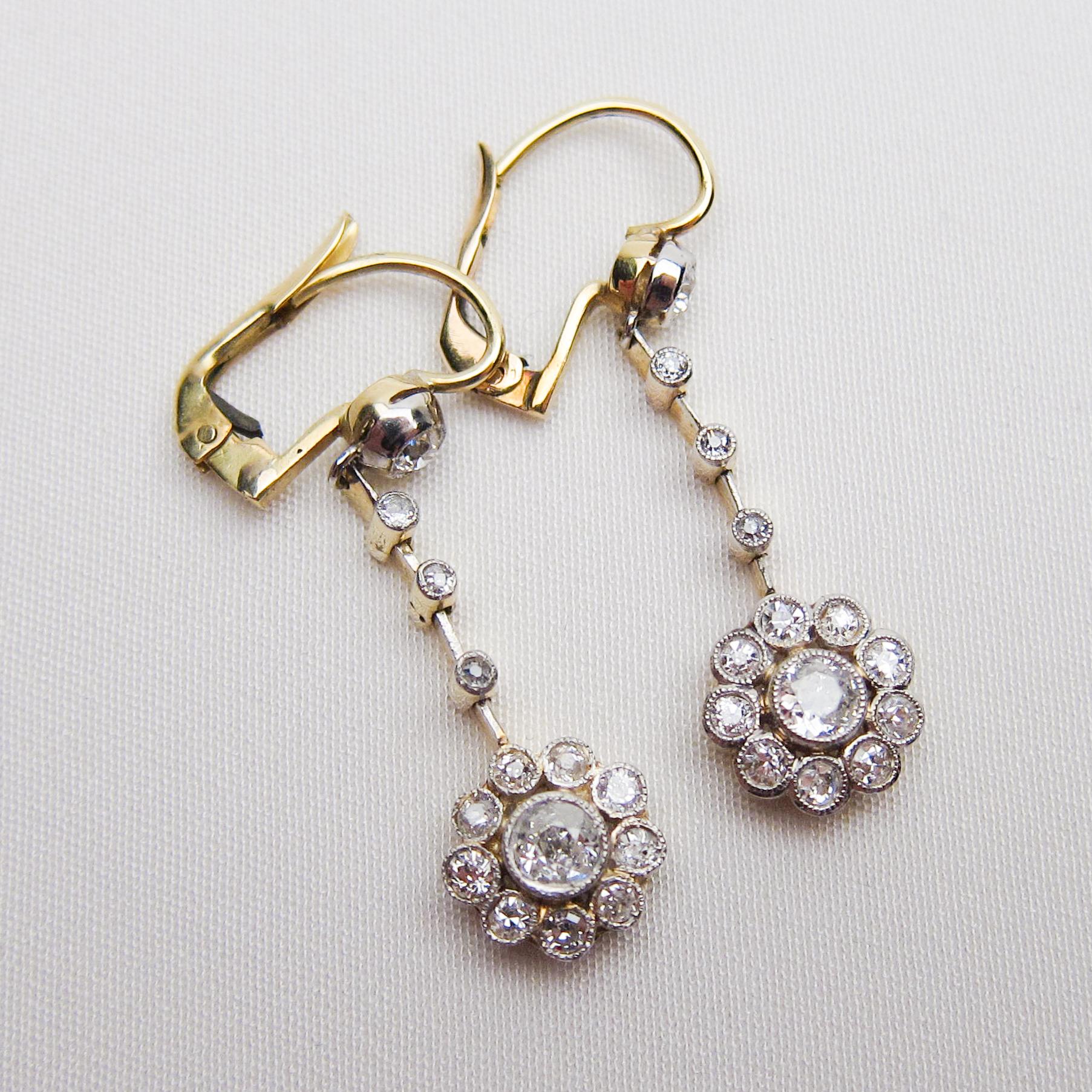 Circa 1910. These lovely floral dangle earrings feature old European-cut diamond clusters fashioned with bezel-set single-cut diamonds, set in platinum-topped 18KT gold. The total diamond weight of both earrings is .84 carats. The diamonds range in