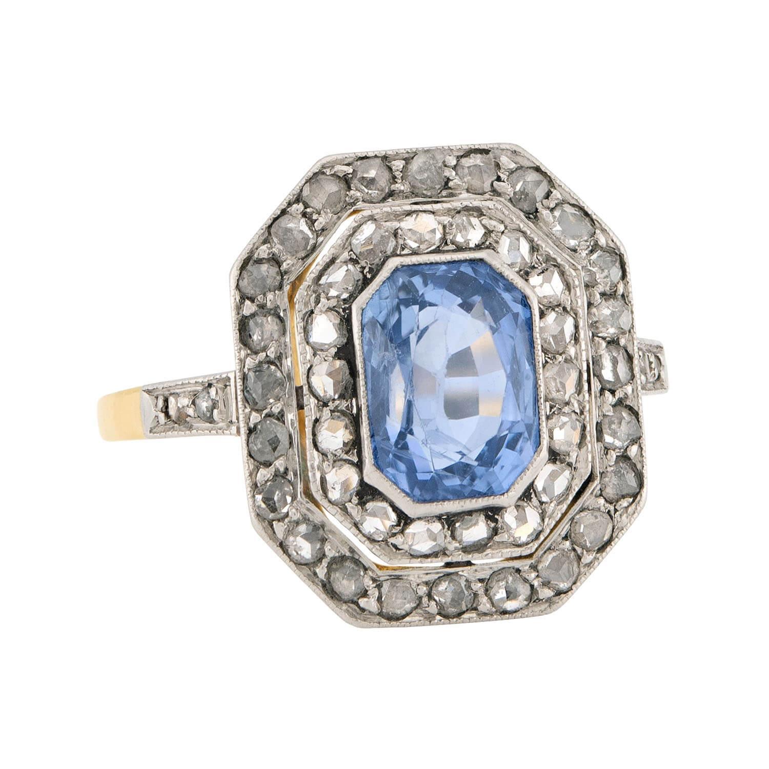 A truly gorgeous ring from the Edwardian (ca1910s) era! Crafted in 18k yellow gold and platinum, this ring features a central no heat 2.35ct emerald cut sapphire. The sapphire is held within a milgrained bezel-setting and displays phenomenal