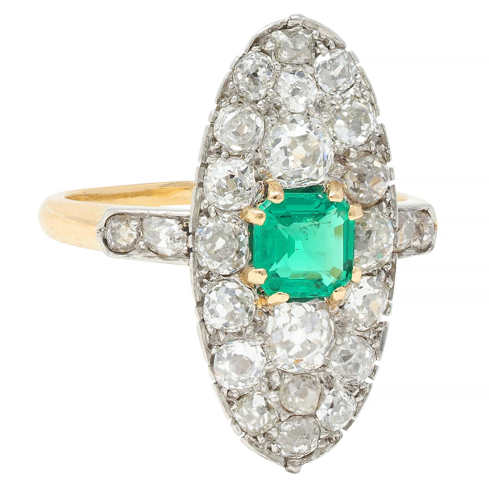 Centering an emerald cut emerald weighing approximately 0.45 carat - transparent medium green
Set with yellow gold split prongs with a recessed navette shaped platinum-topped surround
Prong set throughout form and shoulders with old mine cut