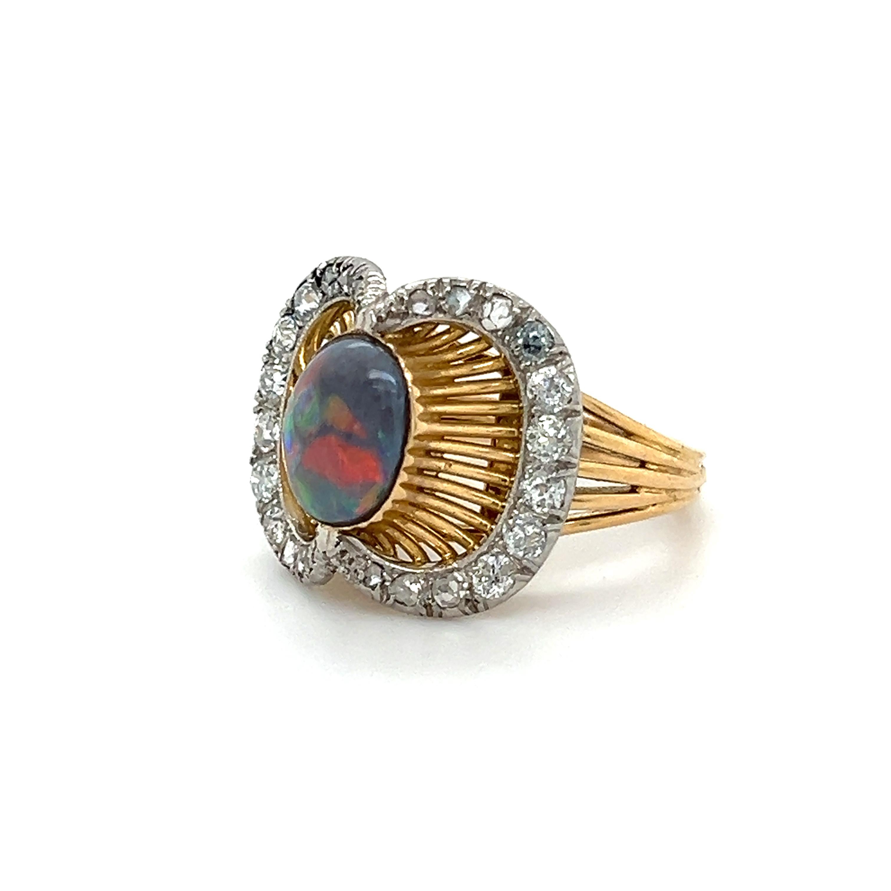 Stand out French Victorian era ring crafted in both platinum and 18k yellow gold. The ring highlights one black opal gemstone. The opal is bezel set and engulfed by a unique cluster of old mined cut diamonds.  Golden wire work forms a bridge that