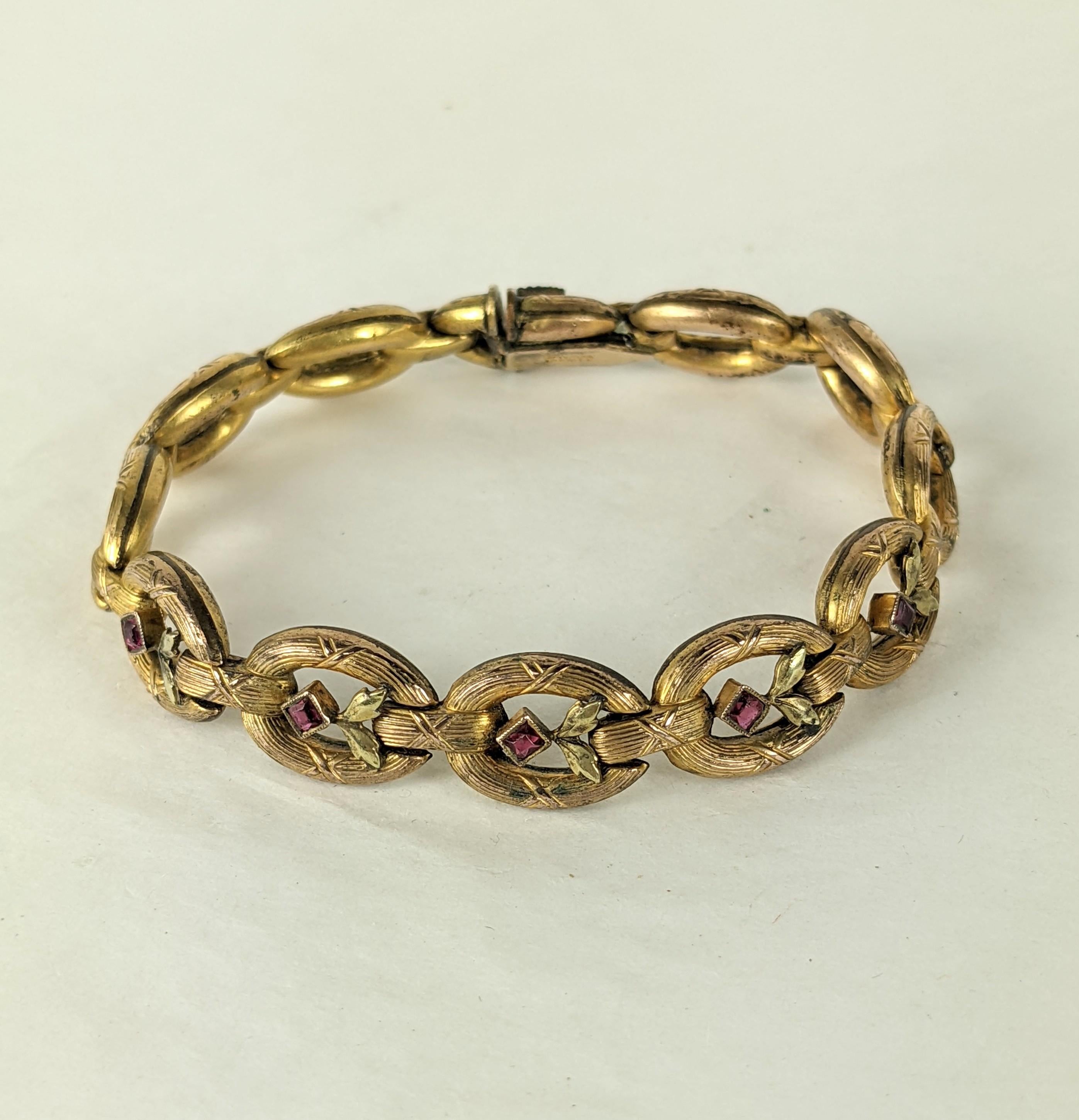 Elegant Edwardian French Gold Filled Link Bracelet circa 1910. Gold toned link with central links decorated with green gold leaves and ruby pastes.  
7