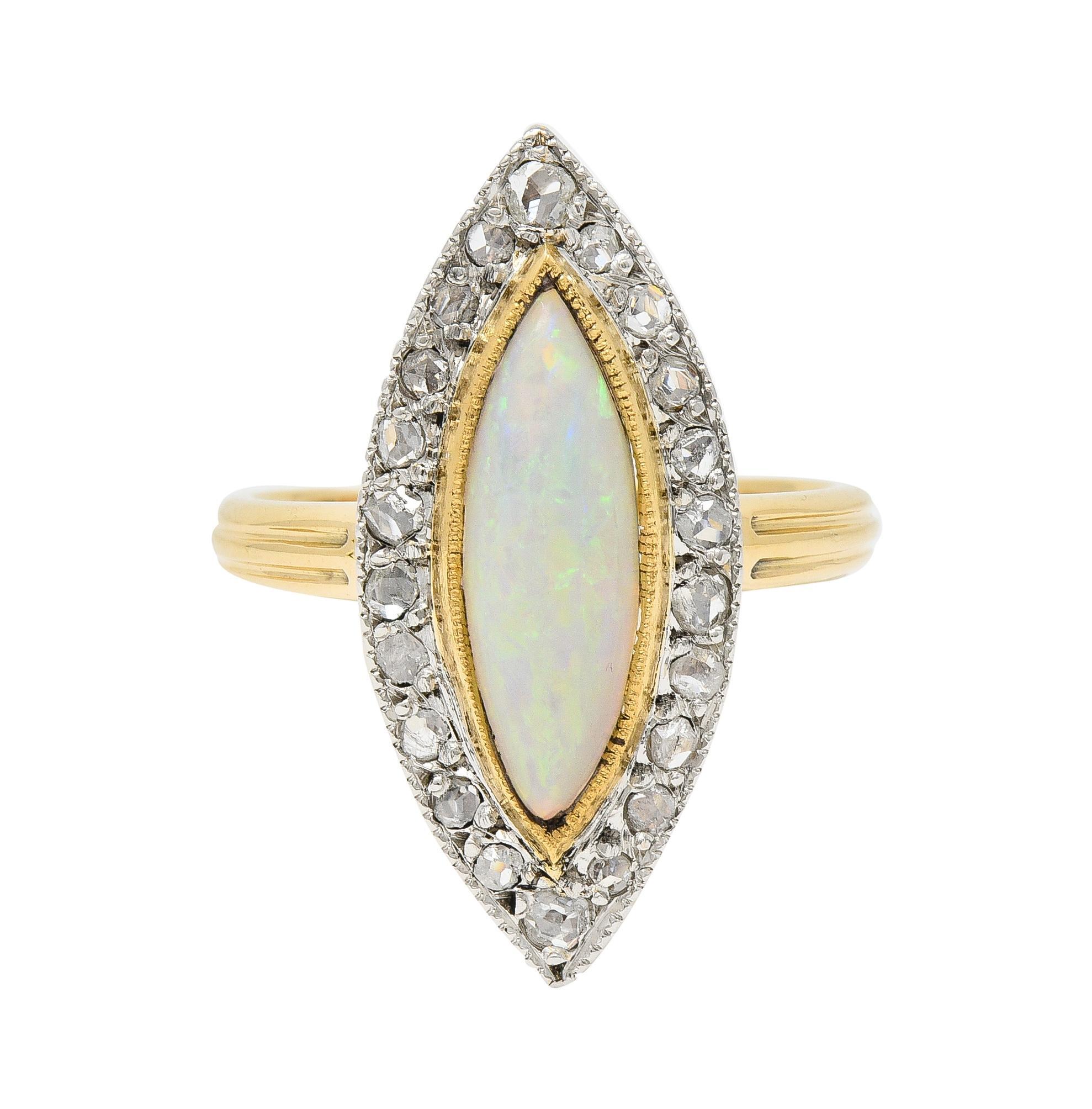 Centering a bezel set navette shape opal cabochon measuring 5.0 x 15.0 mm
Translucent white in body color with spectral play-of-color  
Accented by a halo surround of rose cut diamonds bead set in platinum
Weighing approximately 0.48 carat total -