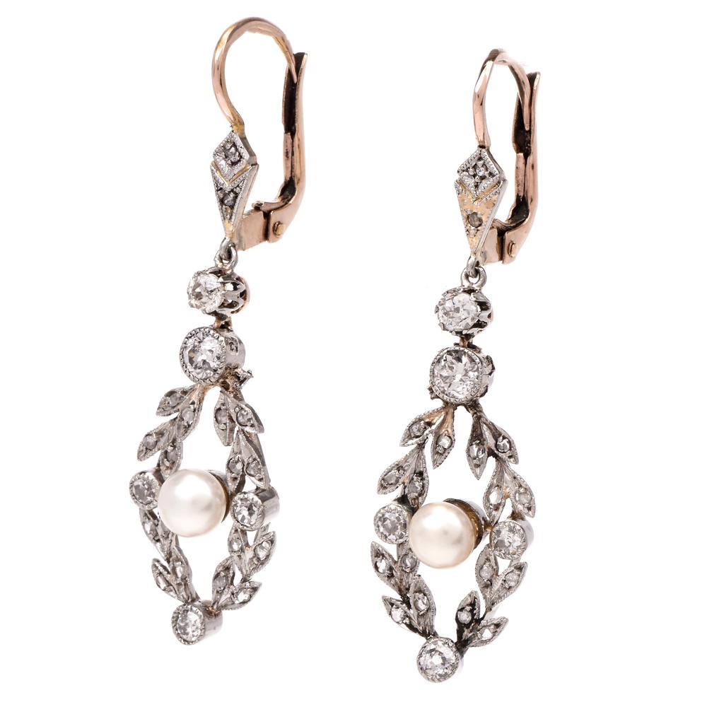These antique garland motifs drop earrings are hand crafted in 18 karat white and rose gold, weigh 6.3 grams and measure 45 mm long and 12 mm wide. The garland motif profiles comprising diamond-studded leaves and buds are enriched with 1.30 carats