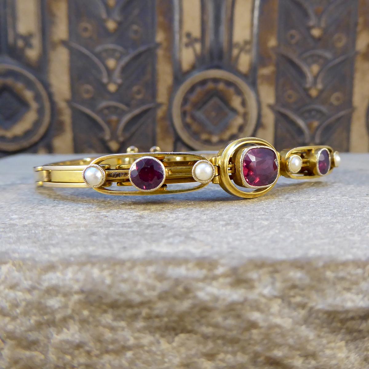 This lovely antique bracelet has been crafted in the Edwardian era from 9ct Yellow Gold, with very clear stamps on the inside. It features 3 Garnets and 4 Pearls alternating across the head of the bracelet attached to an expandable panel bracelet to