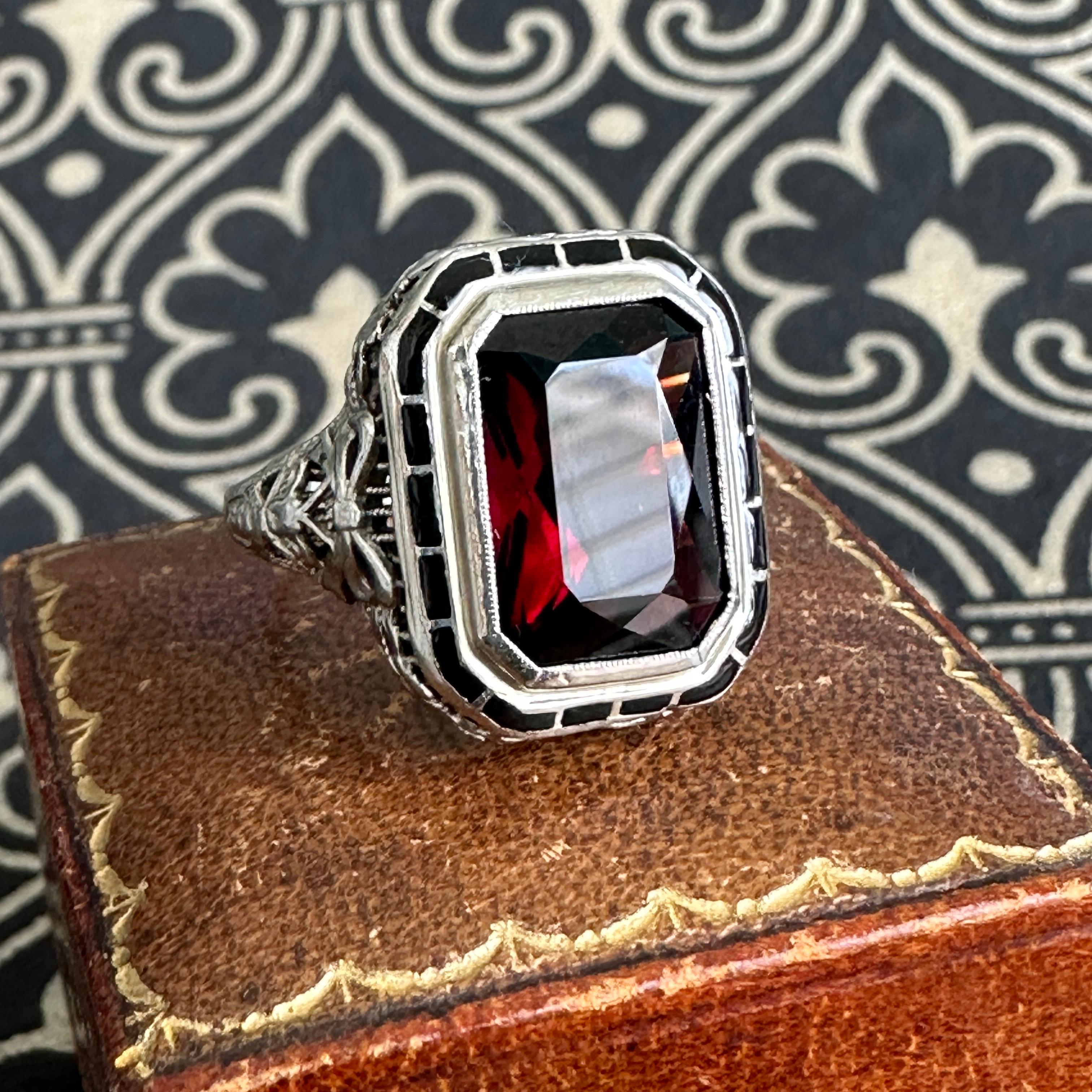 Details: 
A beautiful garnet ring from the Edwardian Era (ca 1900's) era. This lovely ring is crafted in 14K white gold, with black enamel details around the stone. The stone is a beautiful deep red, and measures garnet measures 13mm x 9.66mm. The