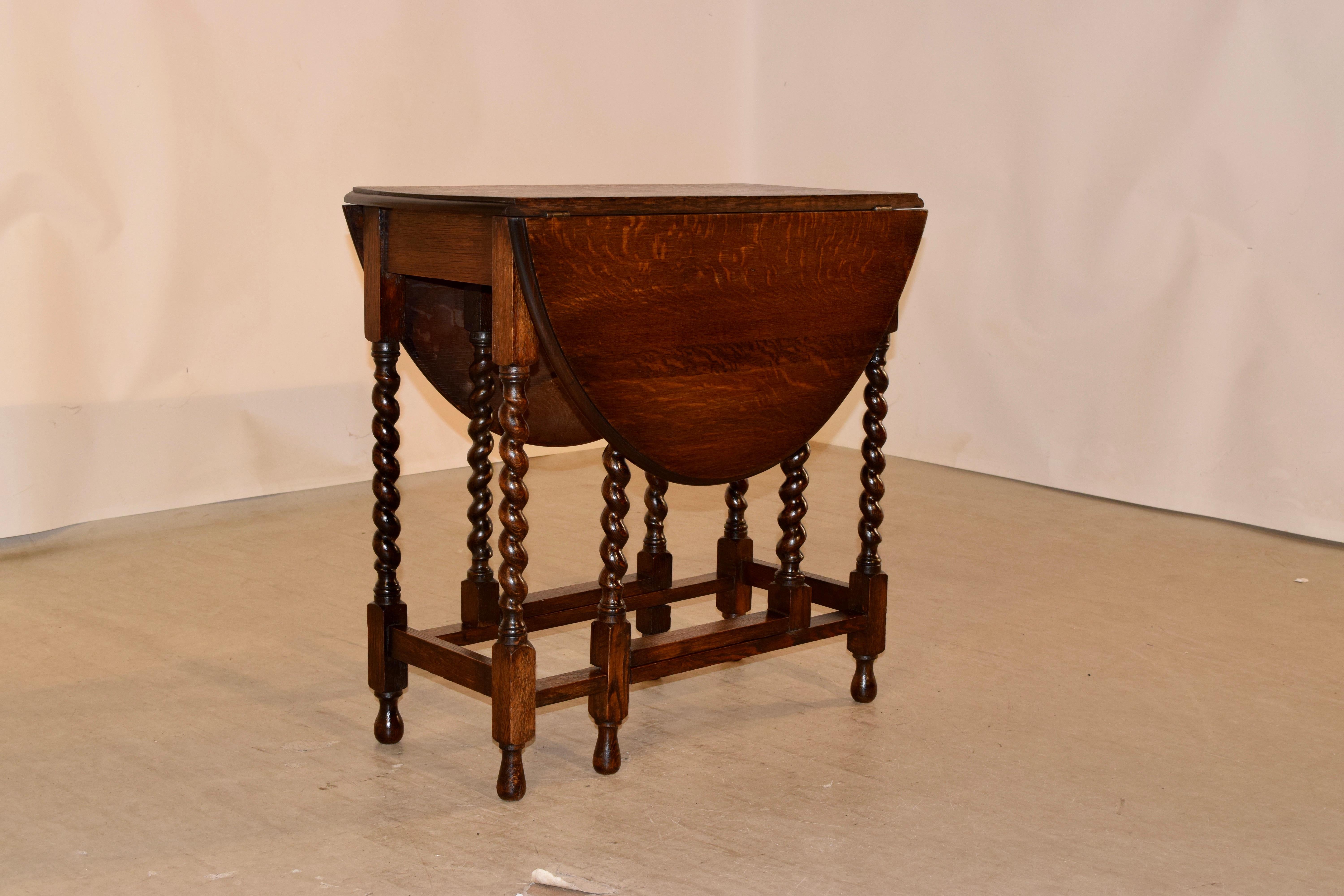 Circa 1900 Edwardian oak gate leg table with two drop leaves. The top has a beveled edge and follows down to a simple apron and is supported on hand turned barley twist legs joined by simple stretchers and hand turned feet. The top open measures