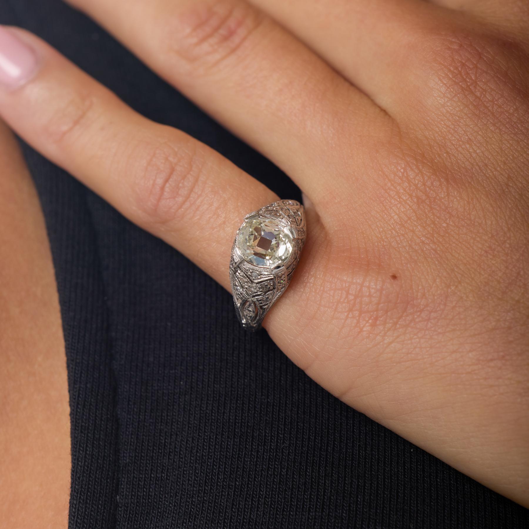 Cette bague de fiançailles édouardienne incarne le raffinement gracieux du début du XXe siècle. Elle est centrée sur un lumineux diamant de taille coussin qui brille chaleureusement dans sa monture en platine. Des dizaines de diamants taille unique