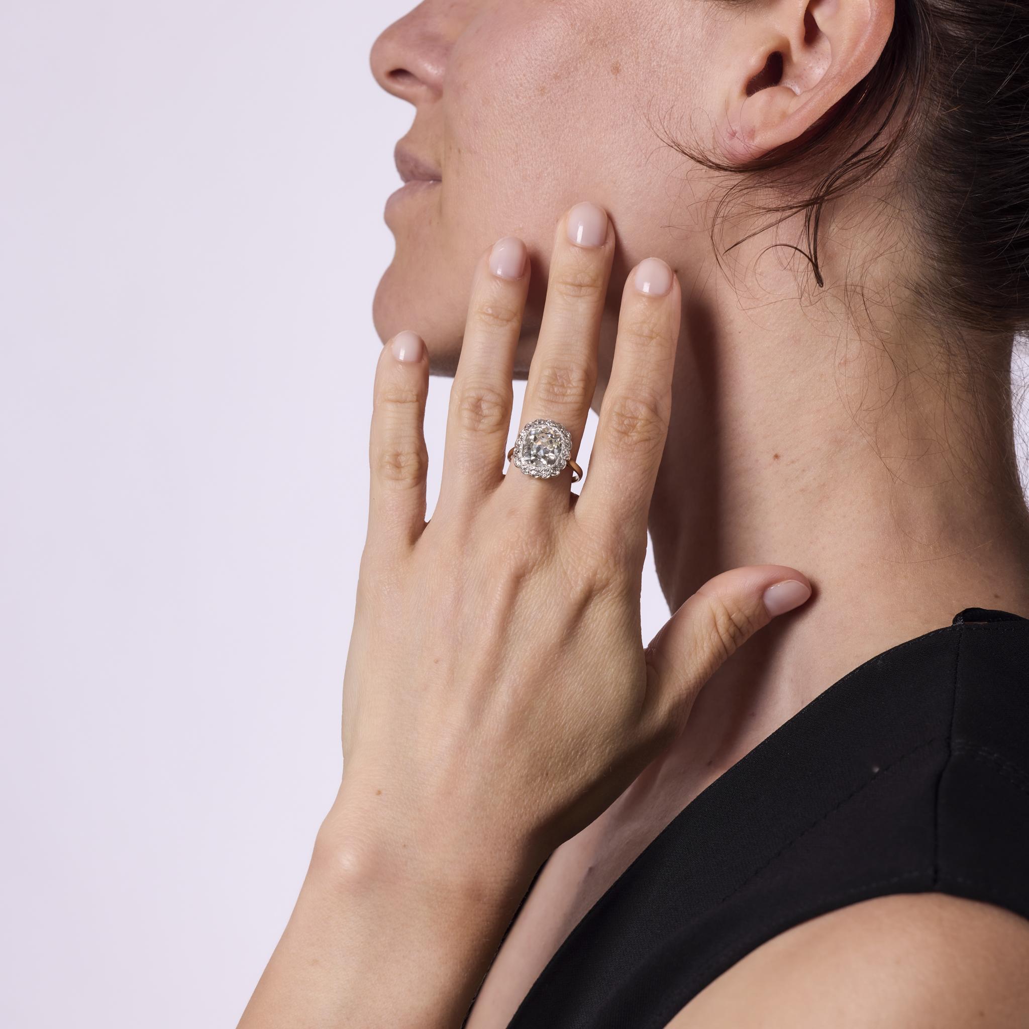 Trésor rare de l'époque édouardienne, cette bague de fiançailles antique est ornée d'un diamant taille ancienne de 5,04 carats certifié par le GIA, d'une couleur K et d'une pureté I1. Entourée de 16 diamants de taille ancienne totalisant environ