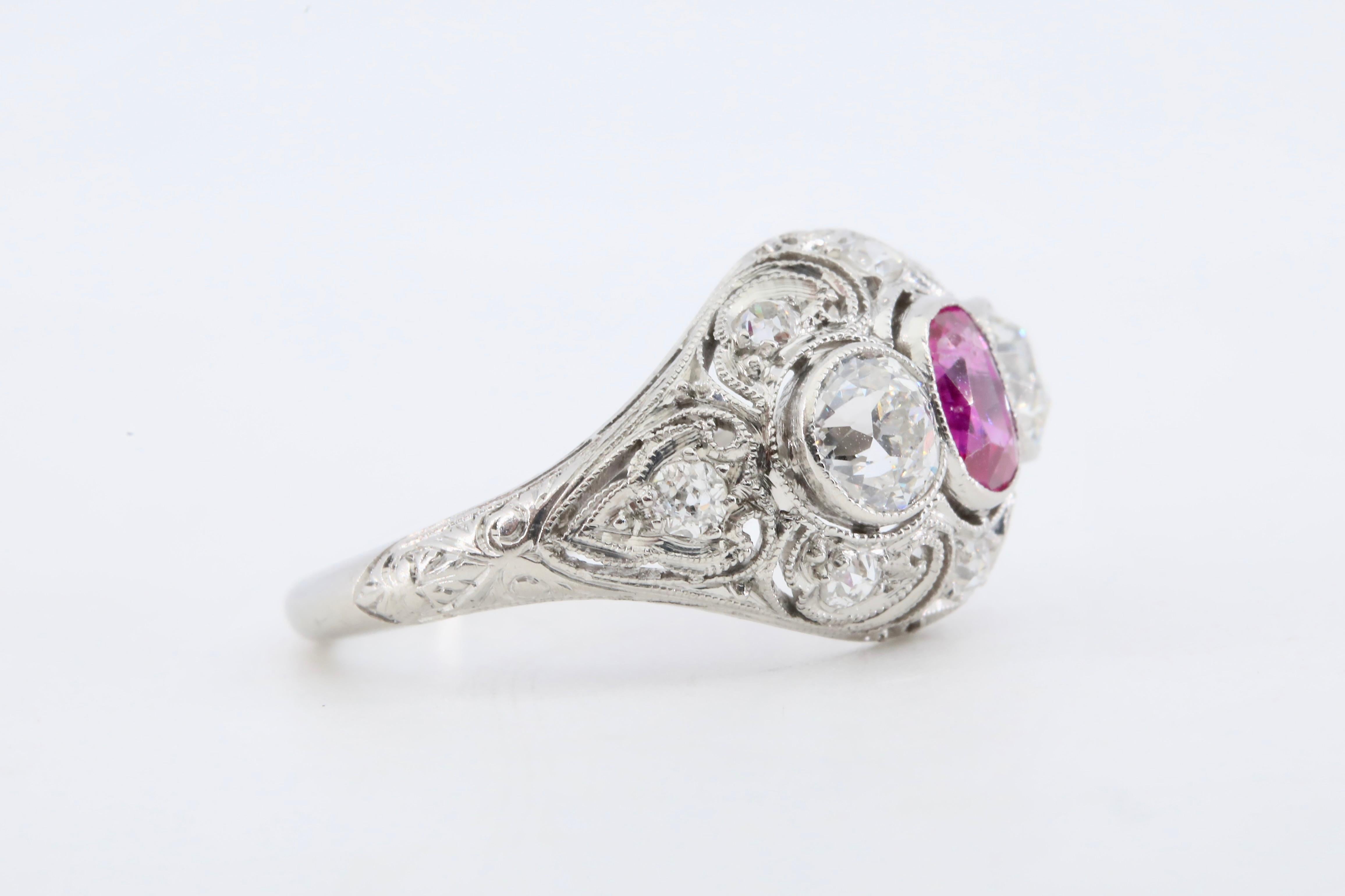 An Edwardian period No Heat Burmese Ruby, and diamond ring in platinum.

Centered by a bezel set old cushion cut ruby of Burma origin with no heat treatment.  The ruby of rich purplish red color with fine clarity and weighing 1.05 carats.

Framed by