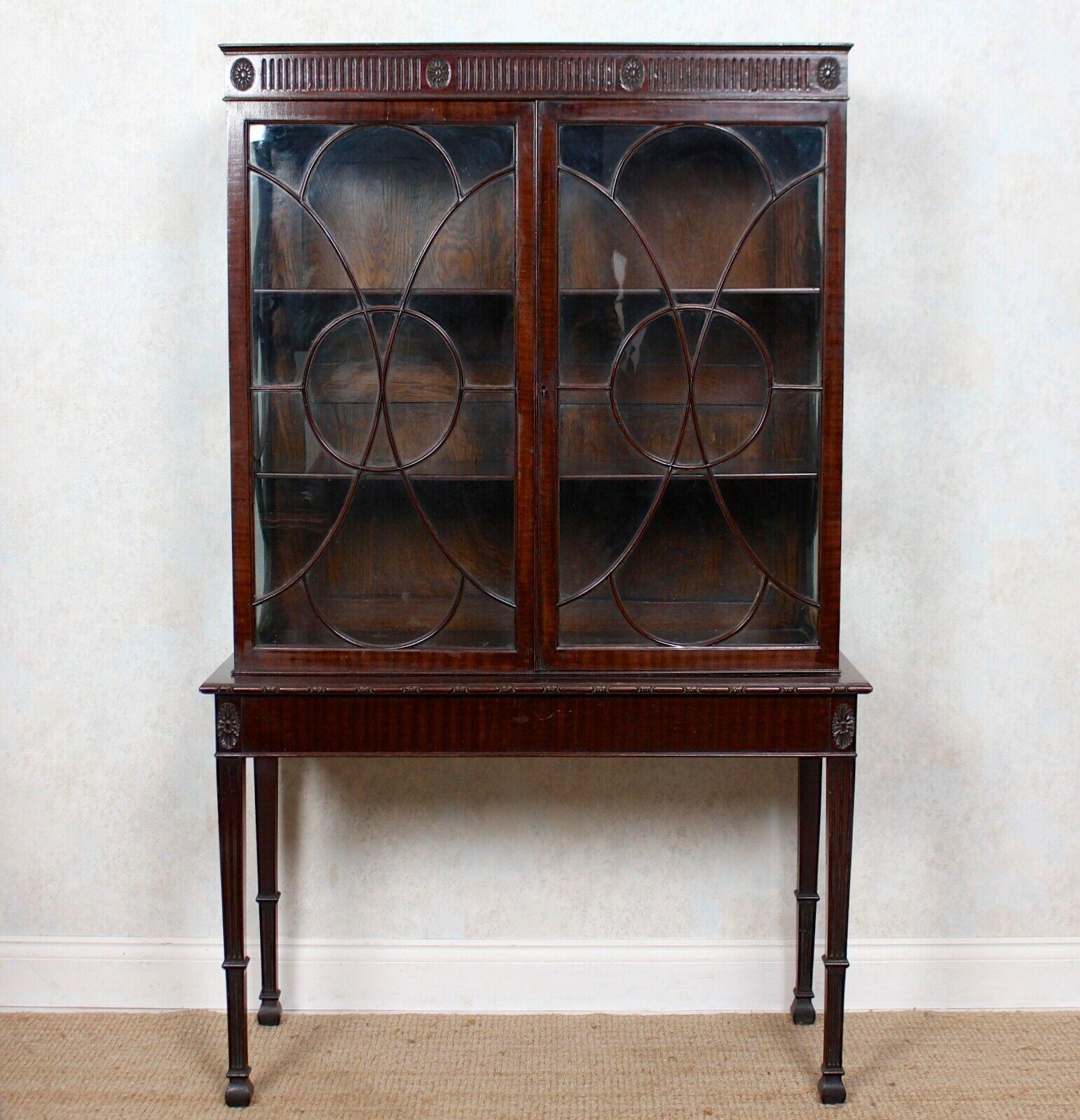 An impressive Edwardian period mahogany display cabinet on stand.

The cornice detailed with flowerhead motifs and reeded borders above astragal glazed doors and sides enclosed shelving. Raised on a stand with mirrored flowerhead motifs on square