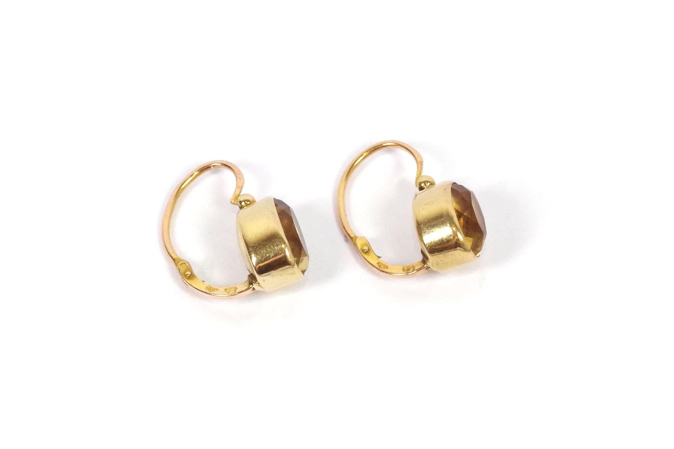 Edwardian gold sleeper earrings in 18 karat rose gold. A pair of earrings featuring a faceted oval yellow glass, imitating citrine, in a closed setting. These are antique earrings from the early 20th century, originating from France.

They bear the