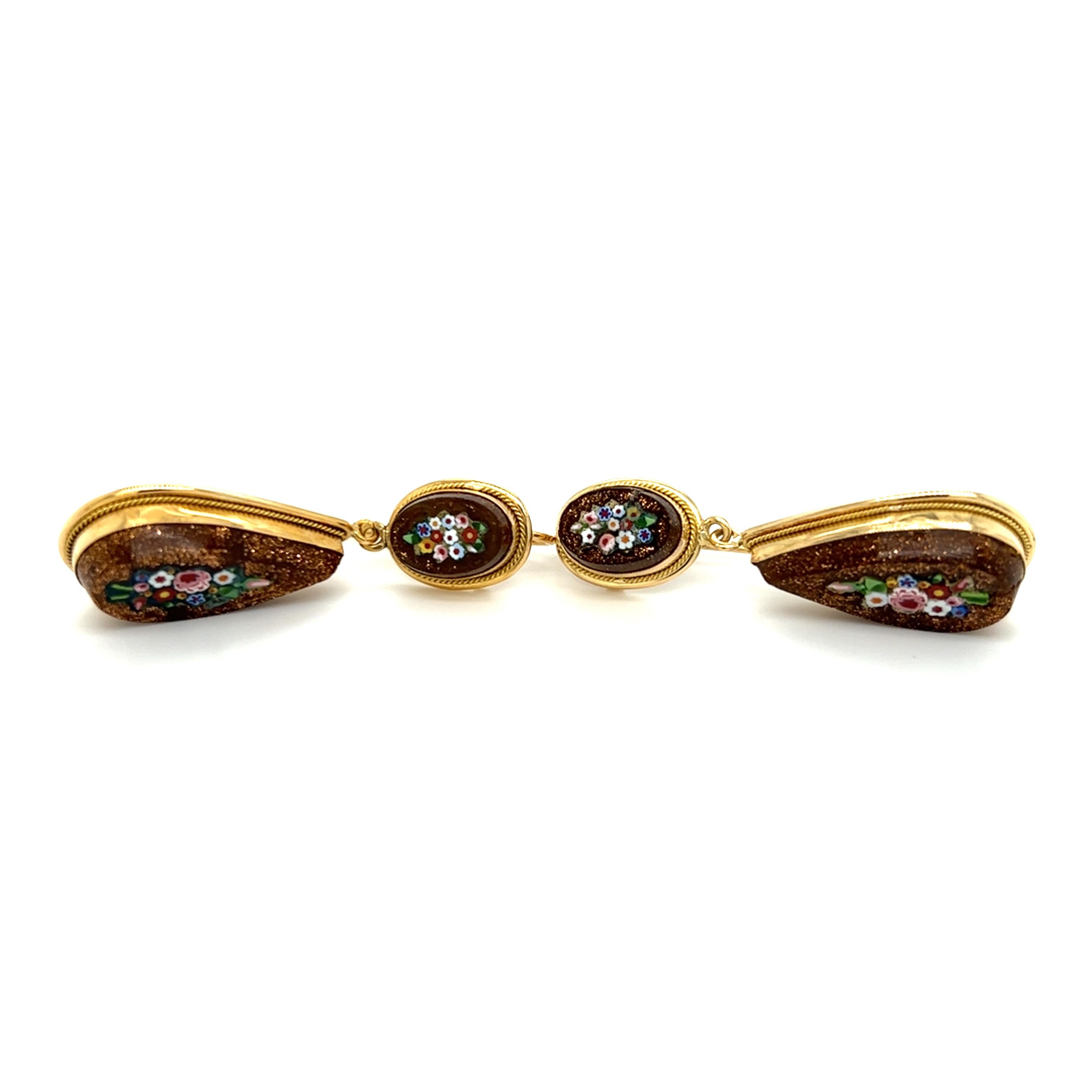 One pair of 18-karat yellow gold (stamped 750) goldstone pendant-style earrings with a tile floral design mosaic inlay. The earrings measure approximately 1.75 inches long and are complete with traditional hook closures.
