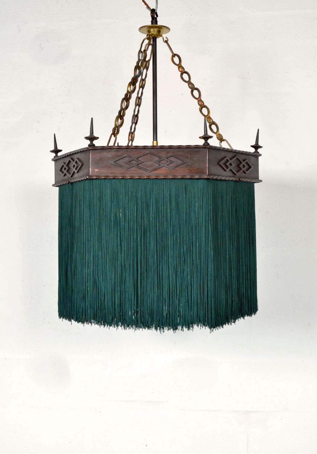 Questa splendida lampada esagonale gotica a sospensione in rame con frangia di nappe verde scuro risale all'epoca edoardiana e sarebbe perfetta sopra un tavolo da pranzo. Ognuno dei sei lati della galleria di rame, da cui pendono le nappe, è