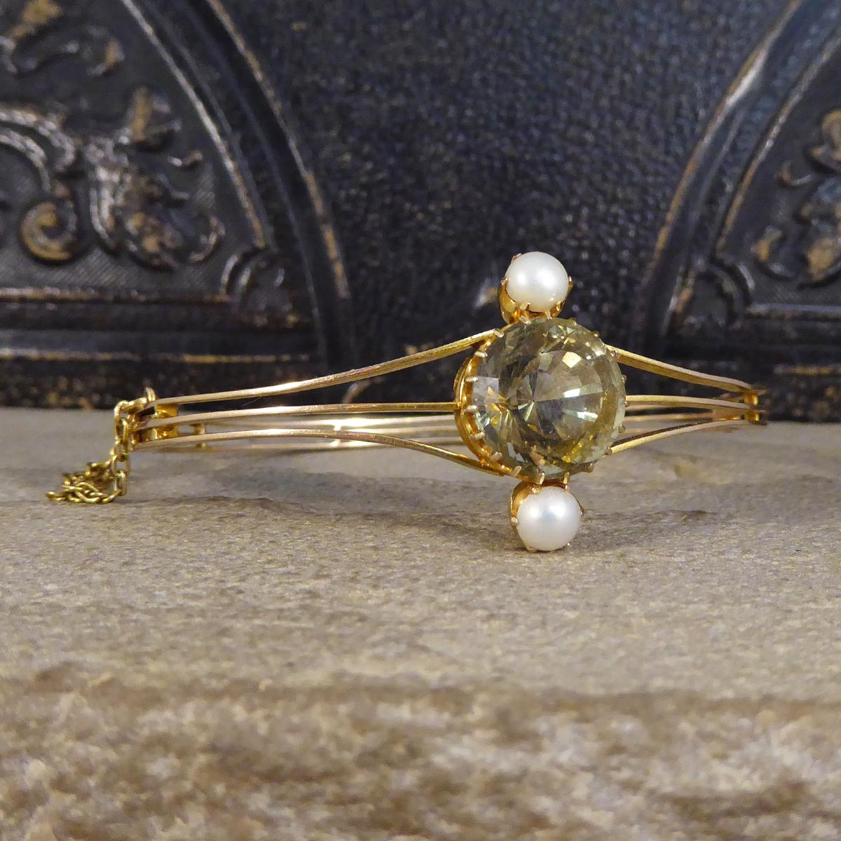 Such a Lovely antique bangle hand crafted in the Edwardian era from 15ct Yellow Gold. It holds an unique Aquamarine in the centre with a greenish colour in a claw setting weighing 6.52ct with a Pearl set above and below. The bangle itself is made