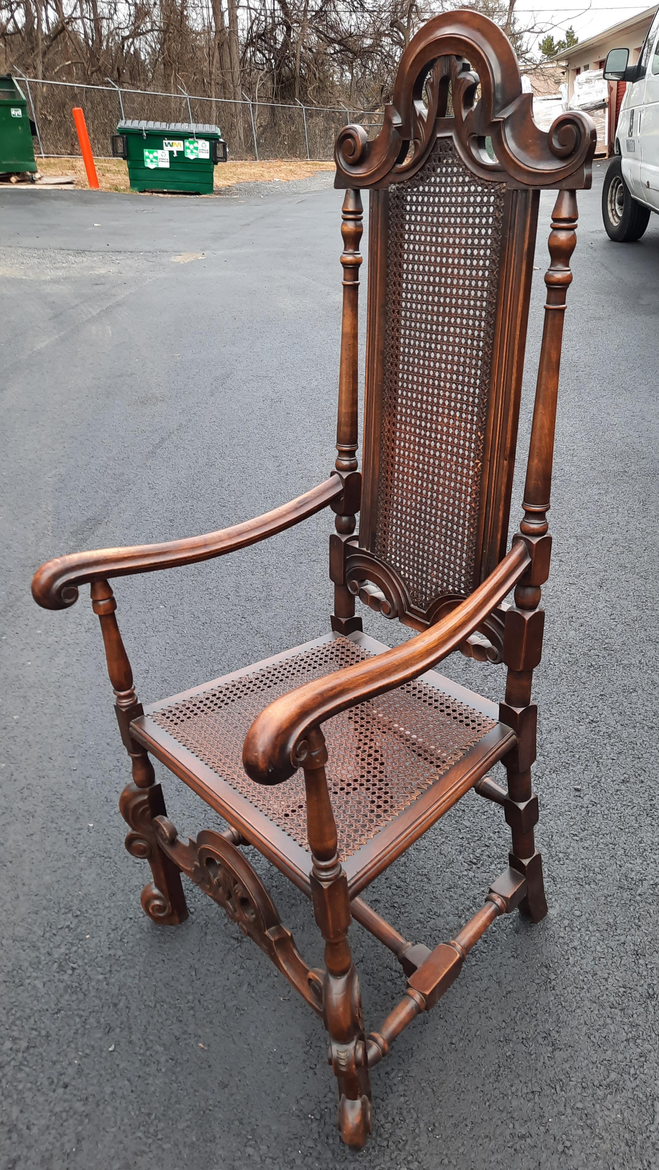 A very decorative antique Edwardian armchair in oak with custom loose cushion. The side supports are turned and topped with a crown. The chair has caned seat and partial back with turned side rails. The chair is very solid and the caning is in very