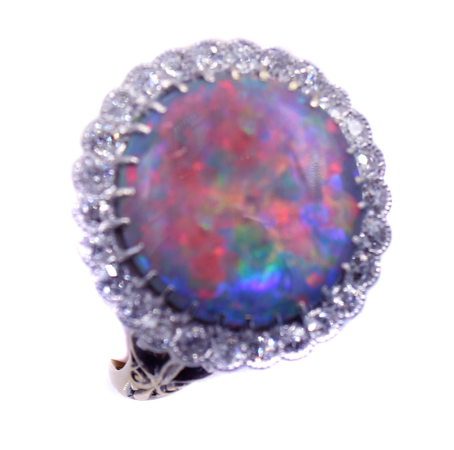 Wonderfully designed and beautifully hand-crafted this Edwardian 18 Karat gold and diamond ring features an Australian Harlequin black opal weighing 4.91 carats. This rare opal exhibits an incredible amount of red, the most sought after color in