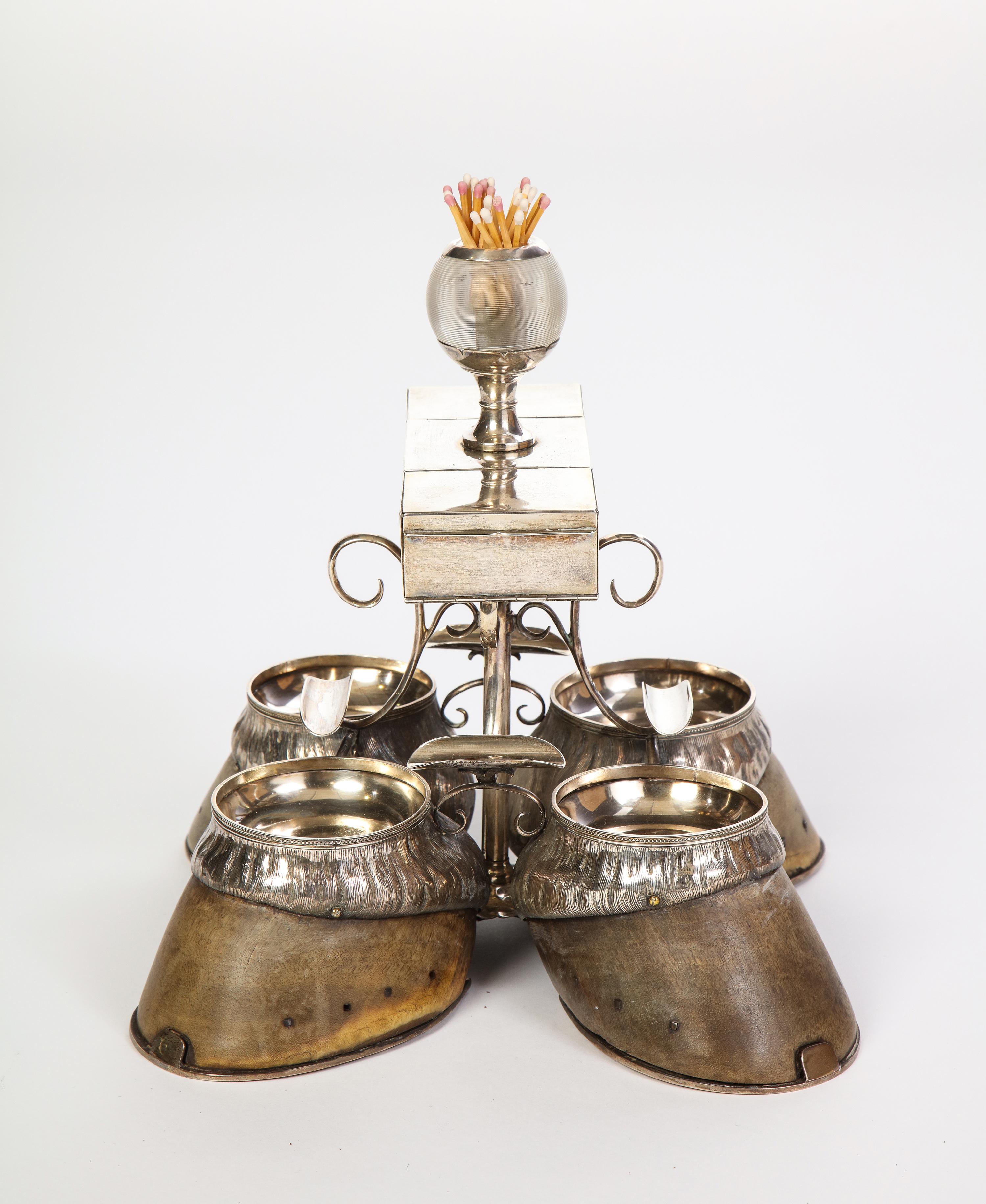 A stately Edwardian antique smoking compendium made circa 1908 by Robert Pringle & Sons. Four sterling silver ashtrays are set into four antique hooves. Mounted above are four graceful silver trays curved to rest a cigarette. The silver compartment